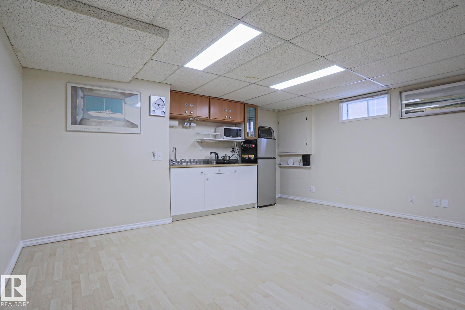 Spacious room featuring light wood-finish flooring and a functional kitchenette - 2433 89 Street, Edmonton, AB - Indoor Photo Showing Basement