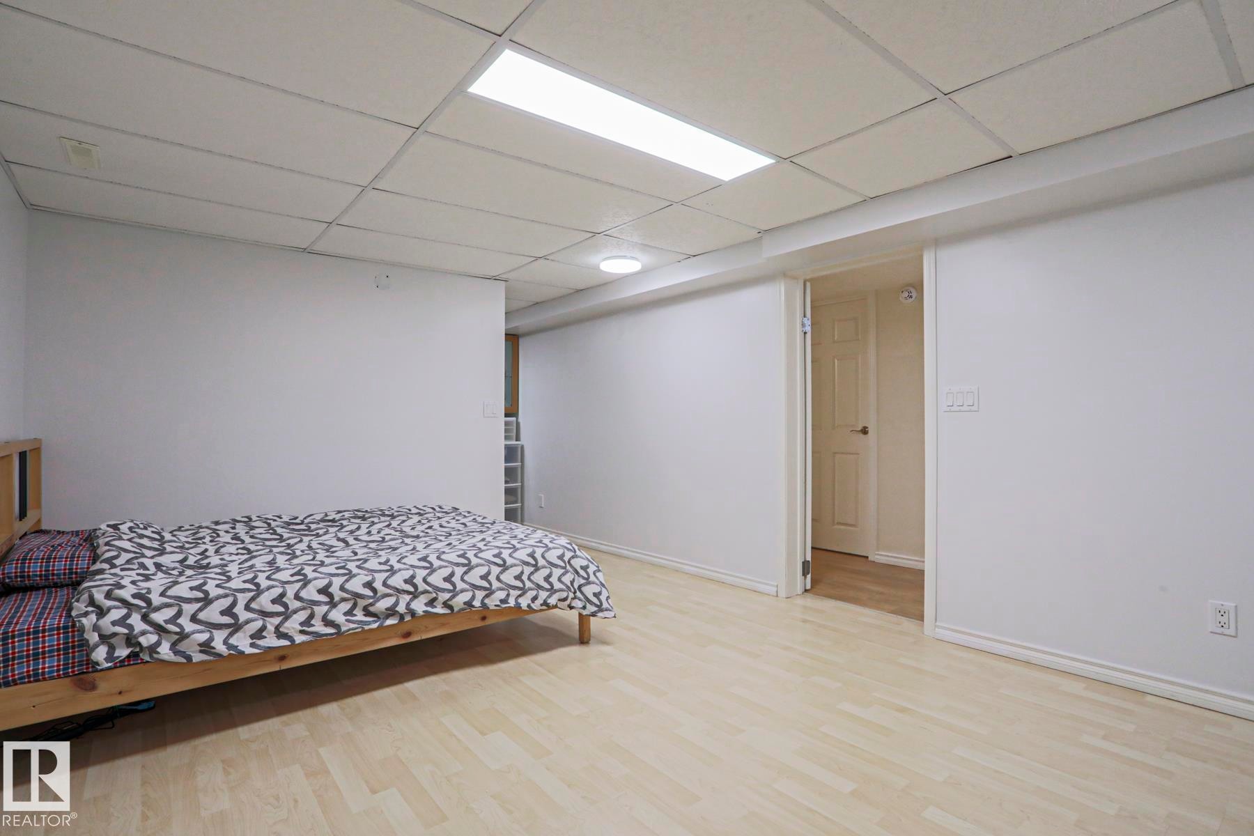 Spacious room featuring light wood-finish flooring, white walls, and a dropped ceiling with recessed lighting - 2433 89 Street, Edmonton, AB - Indoor Photo Showing Bedroom