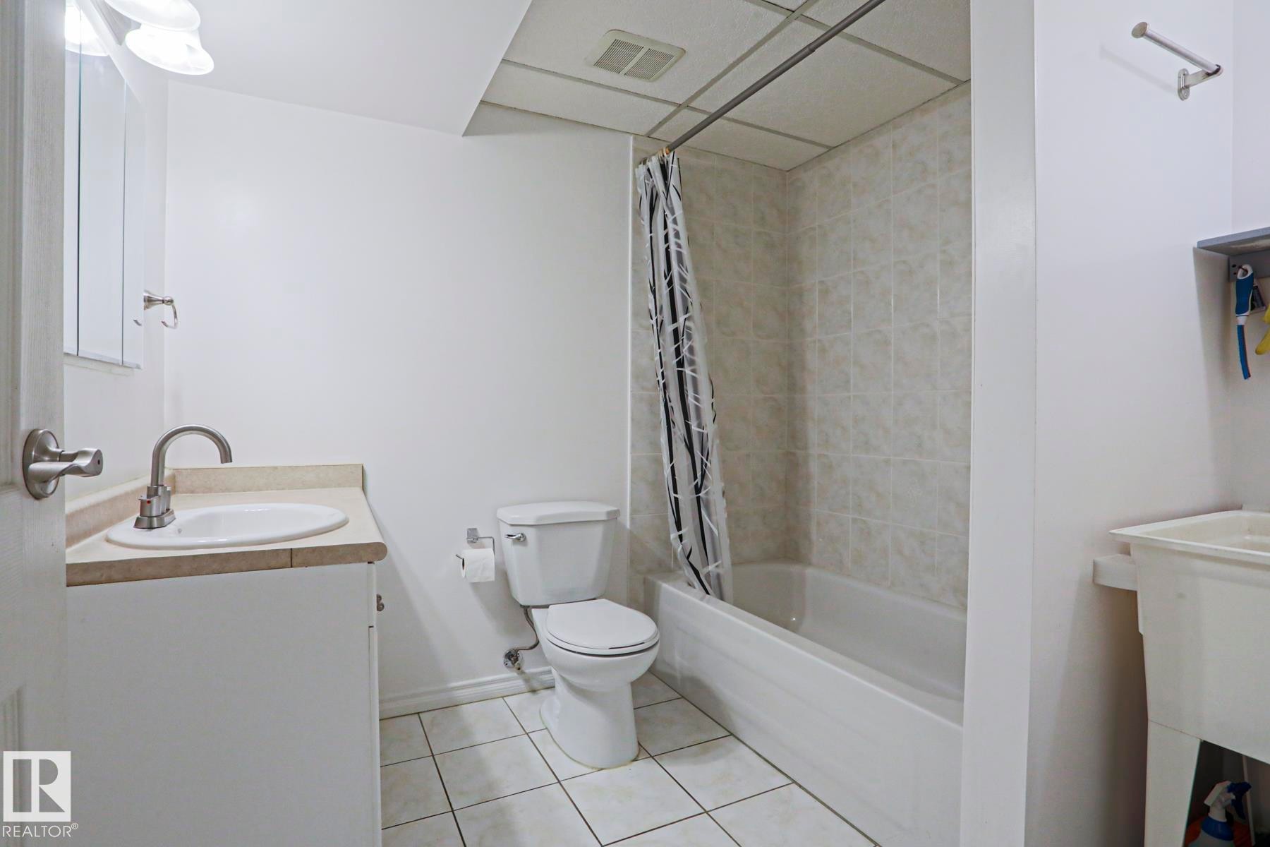 Full bathroom featuring a white vanity with integrated sink, a toilet, and a bathtub with tile surround - 2433 89 Street, Edmonton, AB - Indoor Photo Showing Bathroom