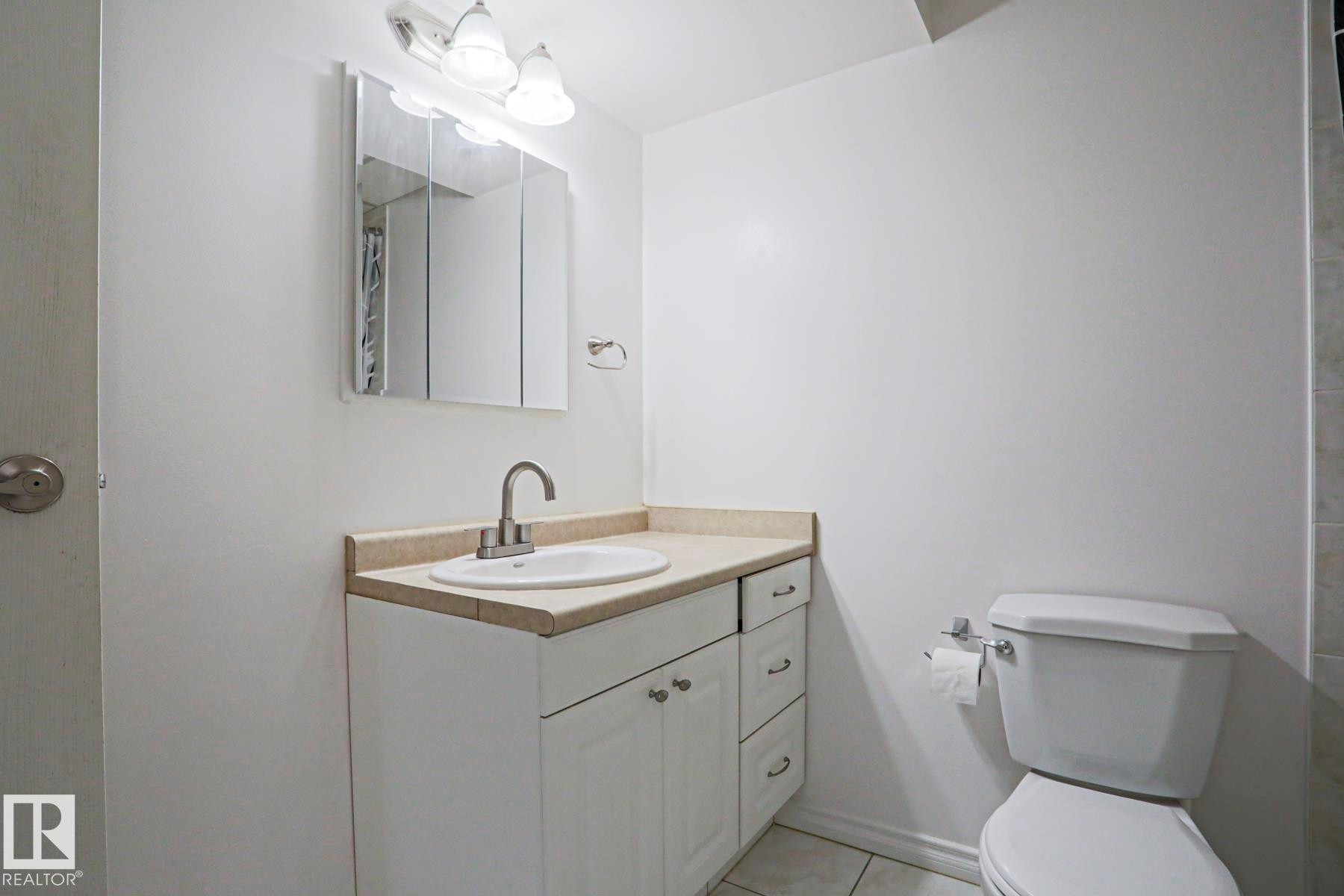 White bathroom vanity with a light-toned countertop, an integrated sink, and a brushed nickel faucet - 2433 89 Street, Edmonton, AB - Indoor Photo Showing Bathroom