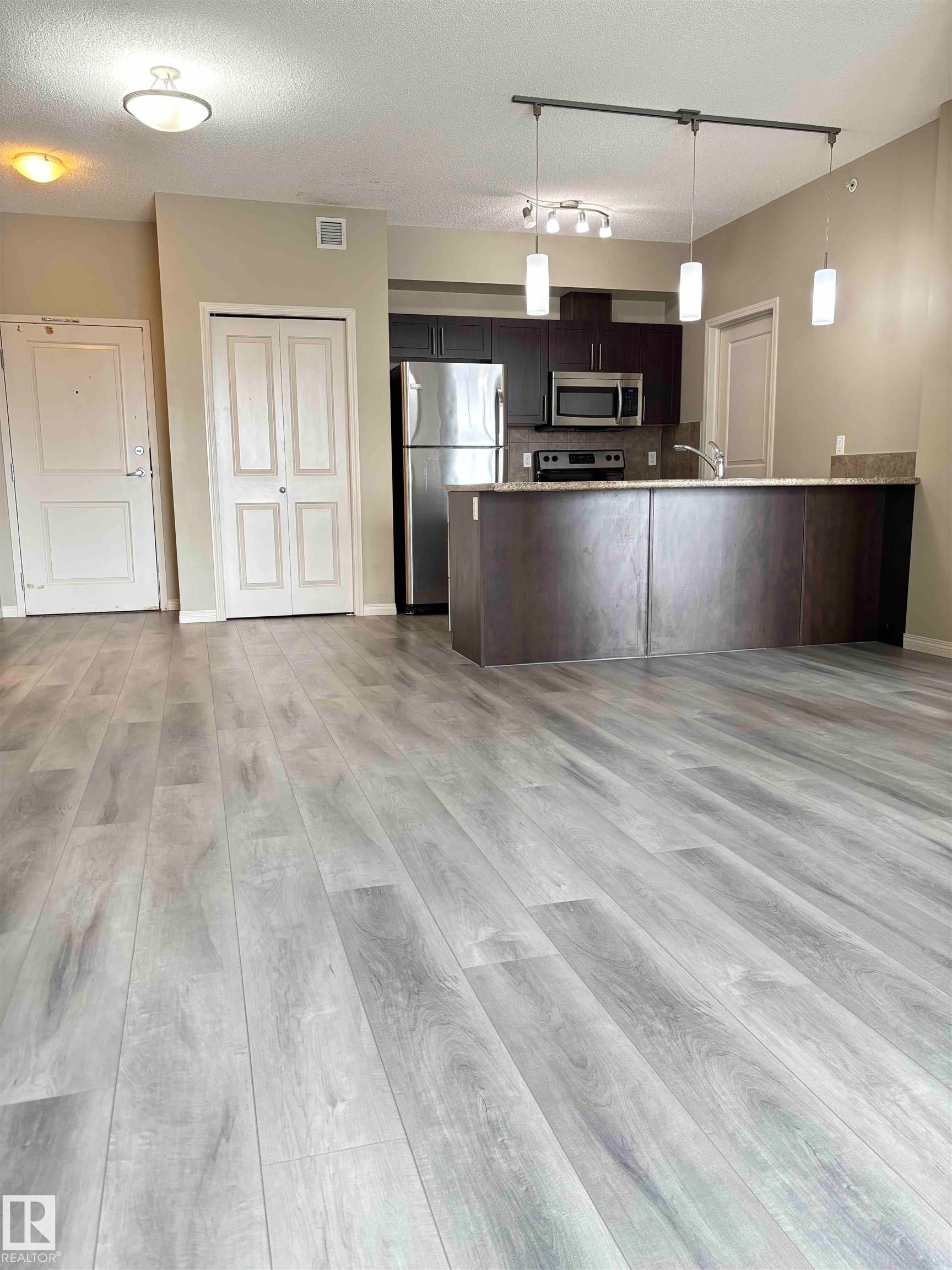 Open-concept living space featuring wood-finish flooring throughout - 408 111 Ambelside Drive Sw, Edmonton, AB - Indoor Photo Showing Kitchen