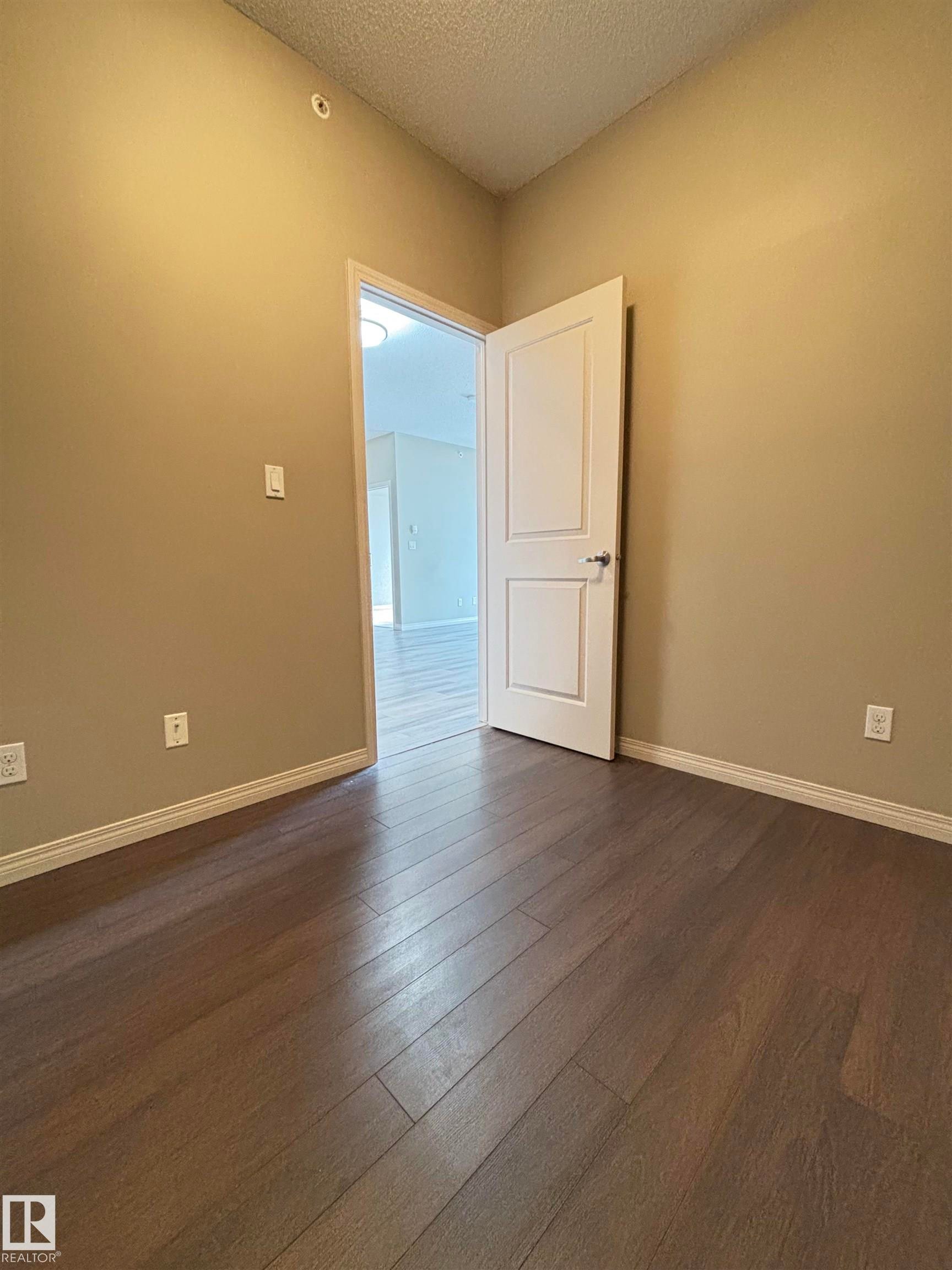 Warm neutral wall tones with wood-finish flooring - 408 111 Ambelside Drive Sw, Edmonton, AB - Indoor Photo Showing Other Room