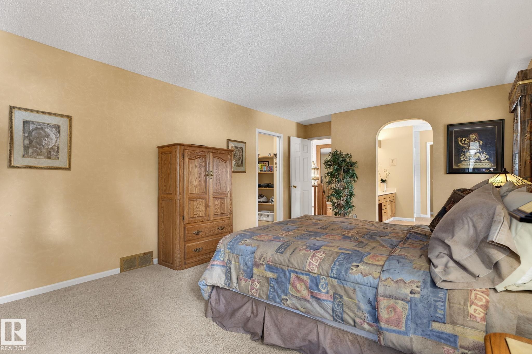 Carpeted room with warm-toned walls, featuring an arched doorway leading to a separate area - 848 Wheeler Road W, Edmonton, AB - Indoor Photo Showing Bedroom