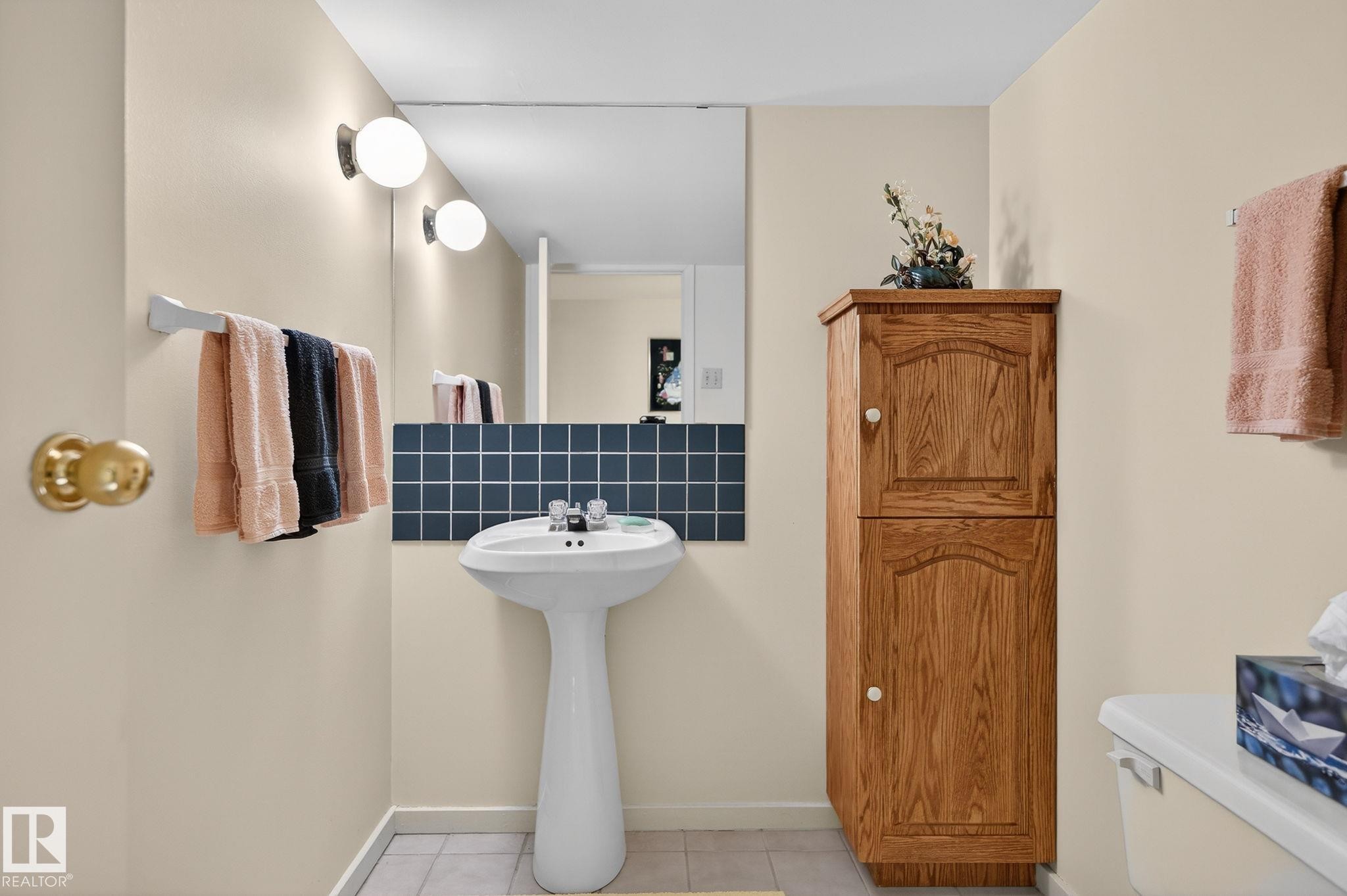 Pedestal sink with dual-handle faucet, full-width wall mirror, and a tiled backsplash - 848 Wheeler Road W, Edmonton, AB - Indoor Photo Showing Bathroom