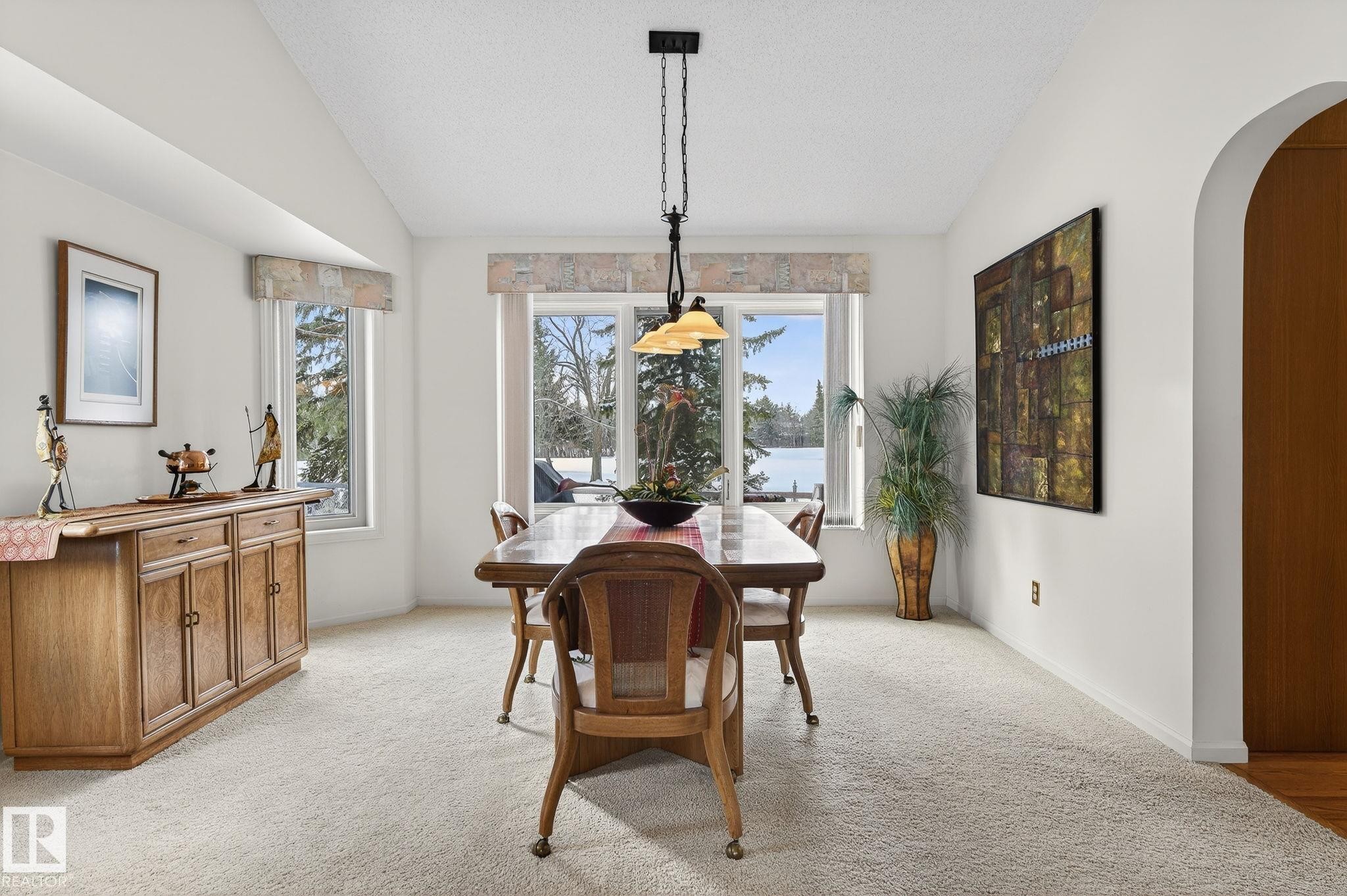 Dining area featuring expansive windows, vaulted ceiling, neutral carpeting, and a built-in arched doorway - 848 Wheeler Road W, Edmonton, AB - Indoor Photo Showing Dining Room