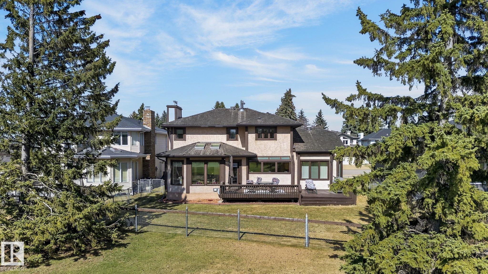 Rear exterior featuring a multi-level deck, stucco finish, multiple windows, and a sunroom with skylights - 848 Wheeler Road W, Edmonton, AB - Outdoor
