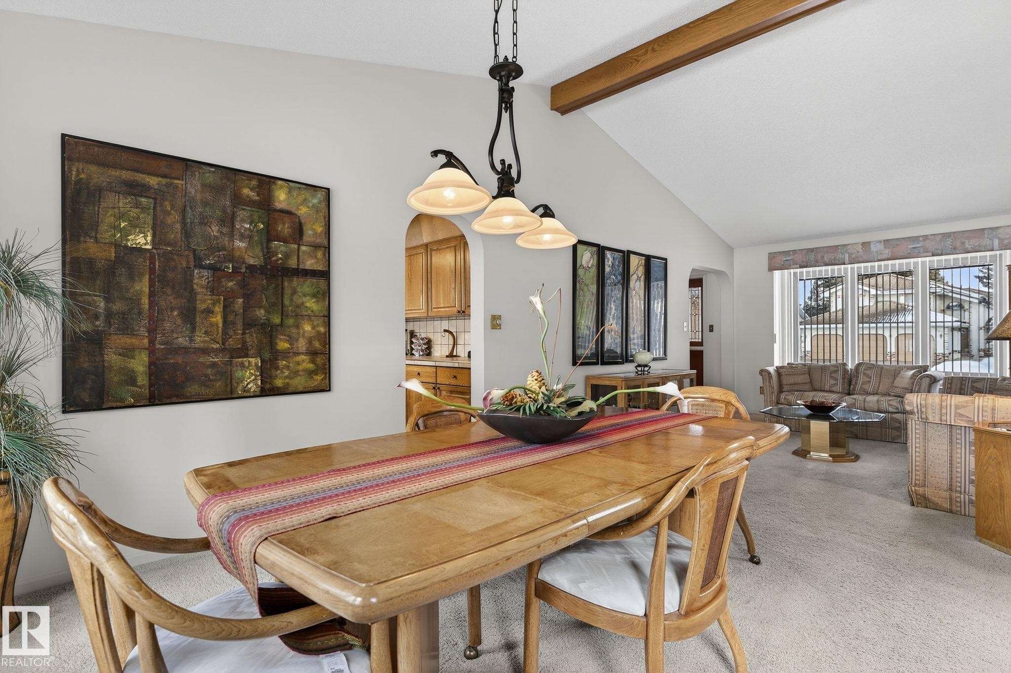 Dining area featuring a vaulted ceiling with exposed wood beams, a three-light chandelier, and an arched doorway - 848 Wheeler Road W, Edmonton, AB - Indoor Photo Showing Dining Room
