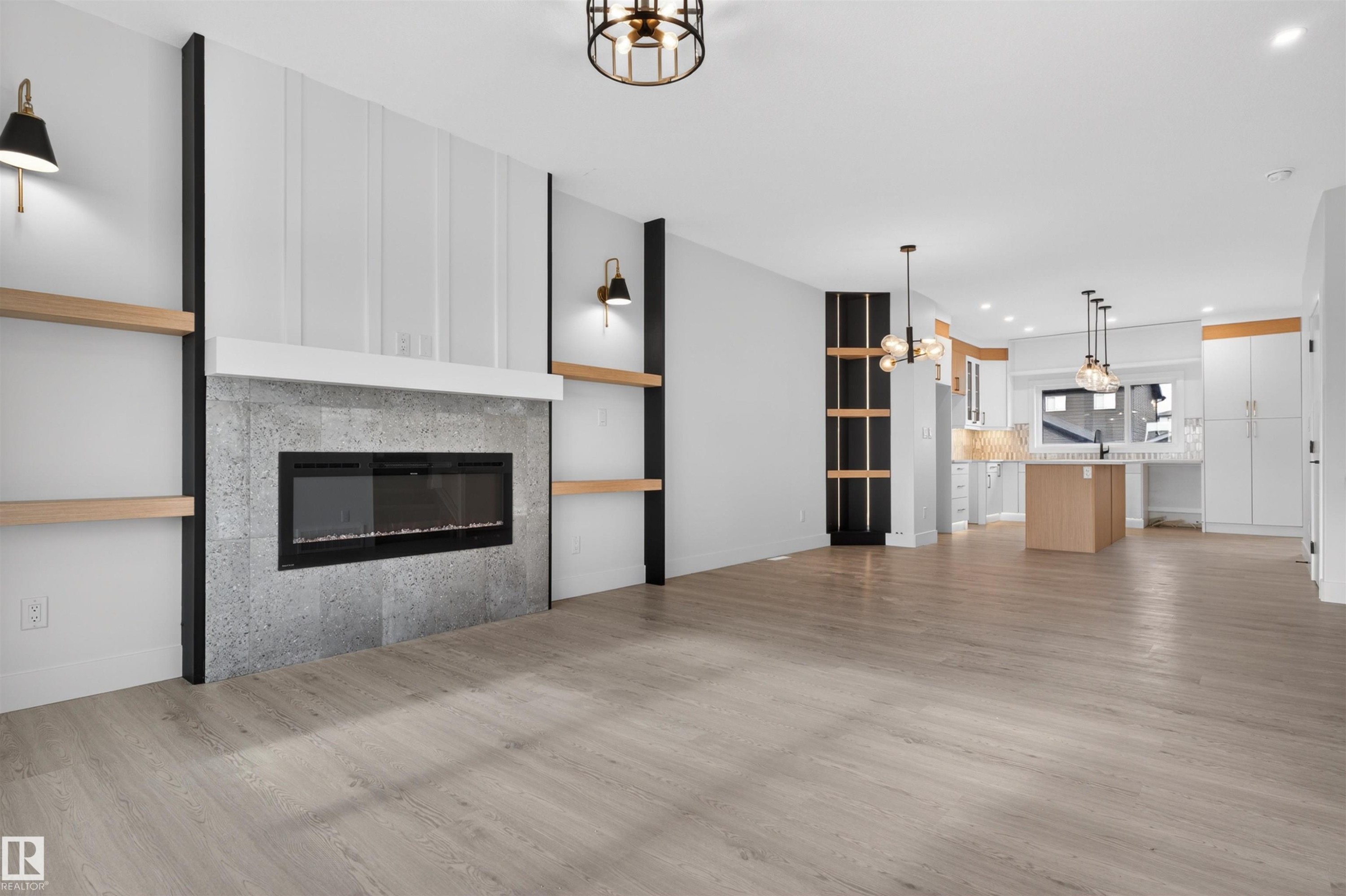 Spacious living area featuring wood-finish flooring and a fireplace with a stone-look surround and white mantel - 45 River Birch, St. Albert, AB - Indoor Photo Showing Living Room With Fireplace