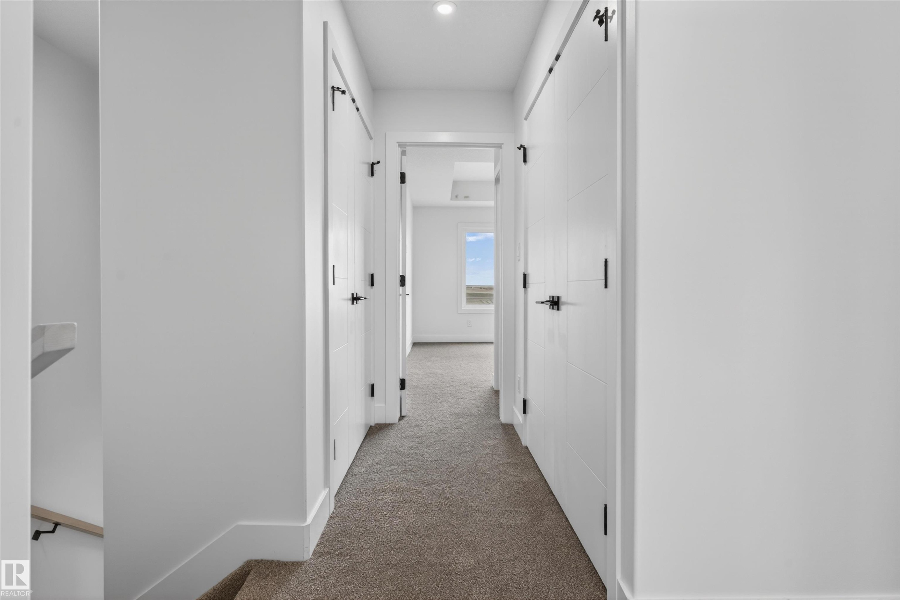 Hallway featuring white panel doors with matte black hardware, recessed lighting, and carpet flooring - 45 River Birch, St. Albert, AB - Indoor Photo Showing Other Room