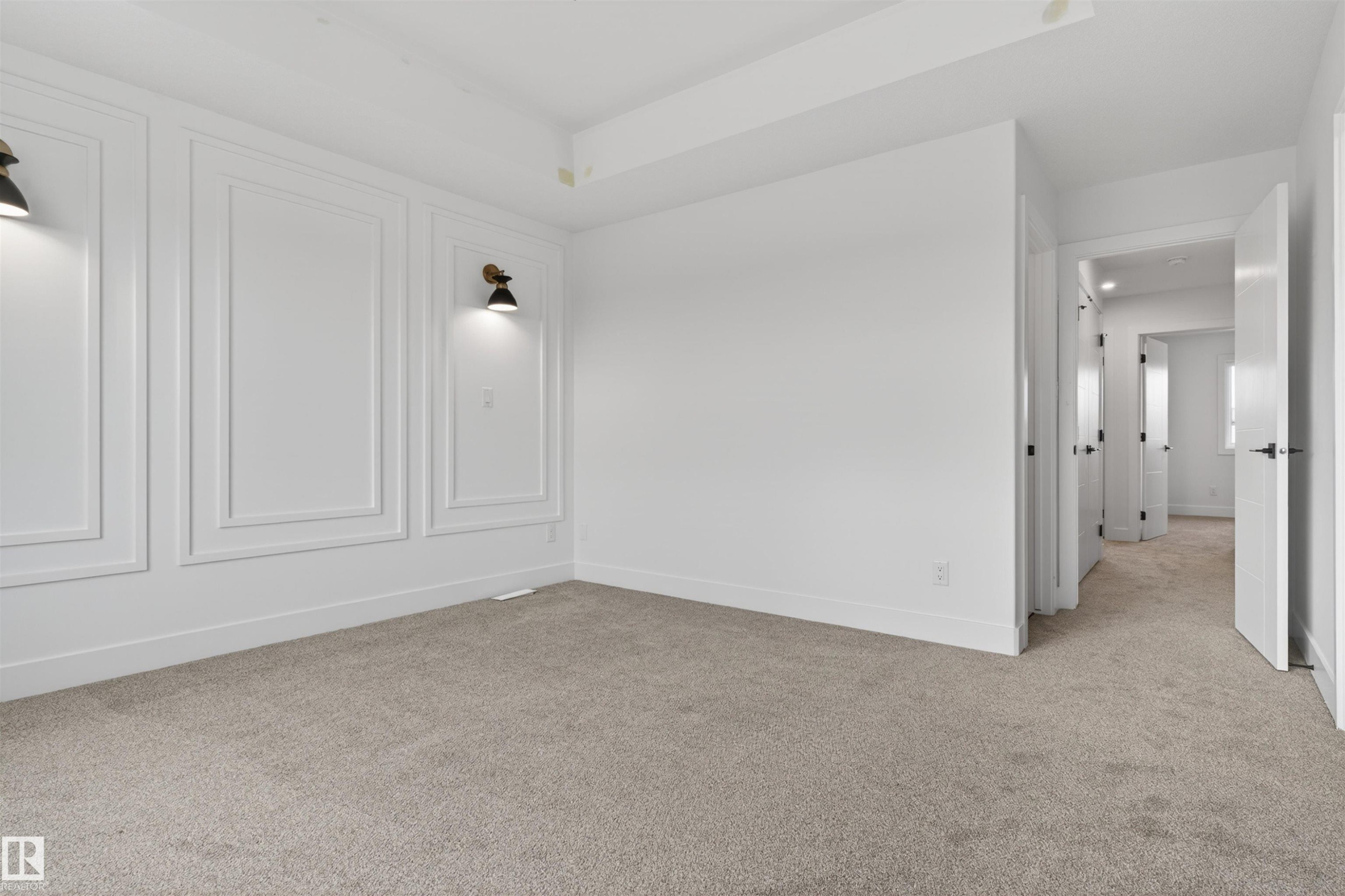 Spacious room featuring carpeted flooring, white baseboards, and a paneled accent wall with integrated sconce lighting - 45 River Birch, St. Albert, AB - Indoor Photo Showing Other Room