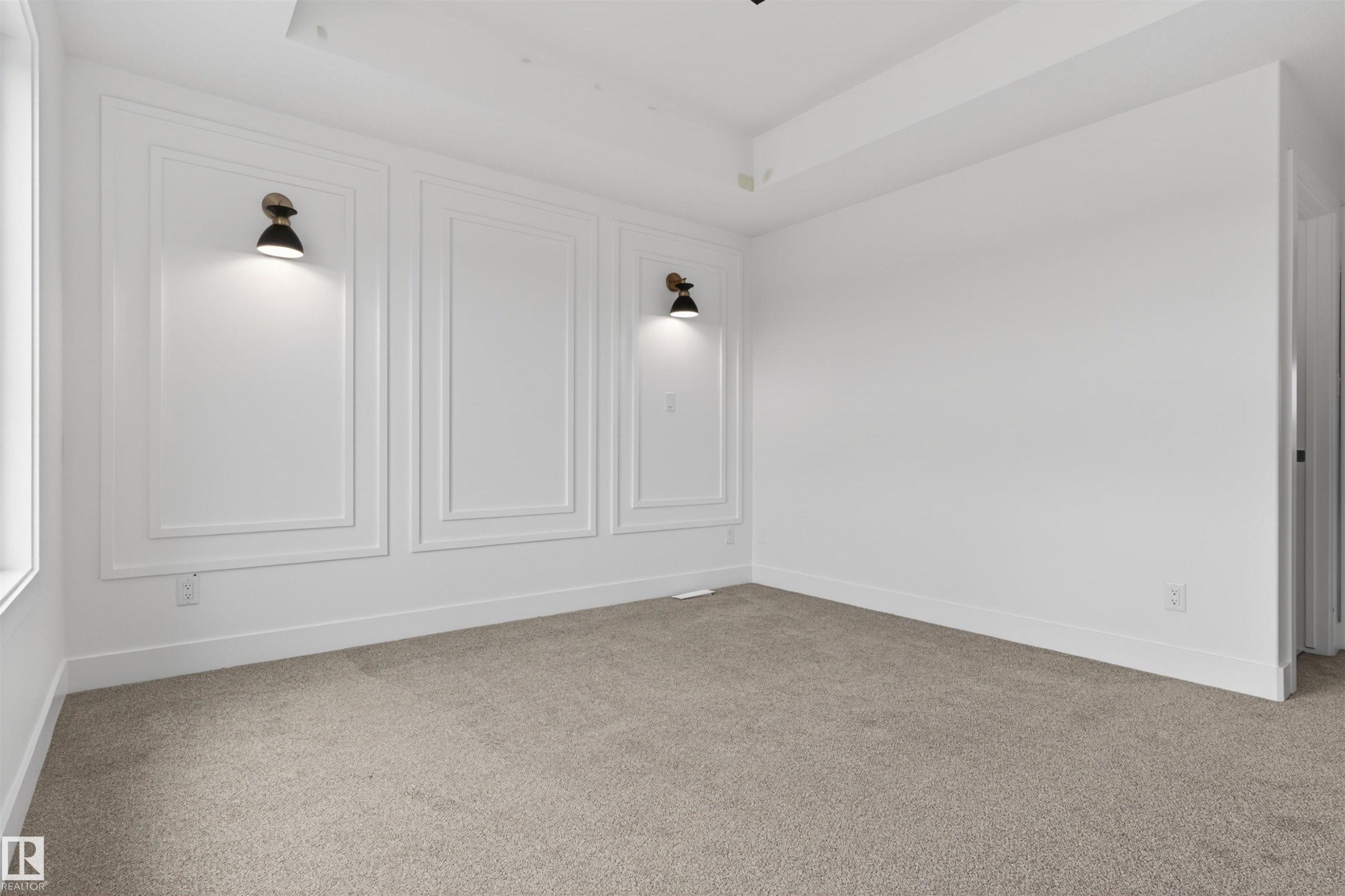 Carpeted interior space featuring decorative wall molding with integrated sconce lighting, white baseboards, and a tray ceiling - 45 River Birch, St. Albert, AB - Indoor Photo Showing Other Room