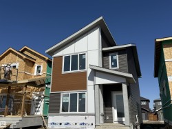 Contemporary exterior featuring multi-toned siding, a prominent covered entry, multiple large windows, and a distinctive roofline -
