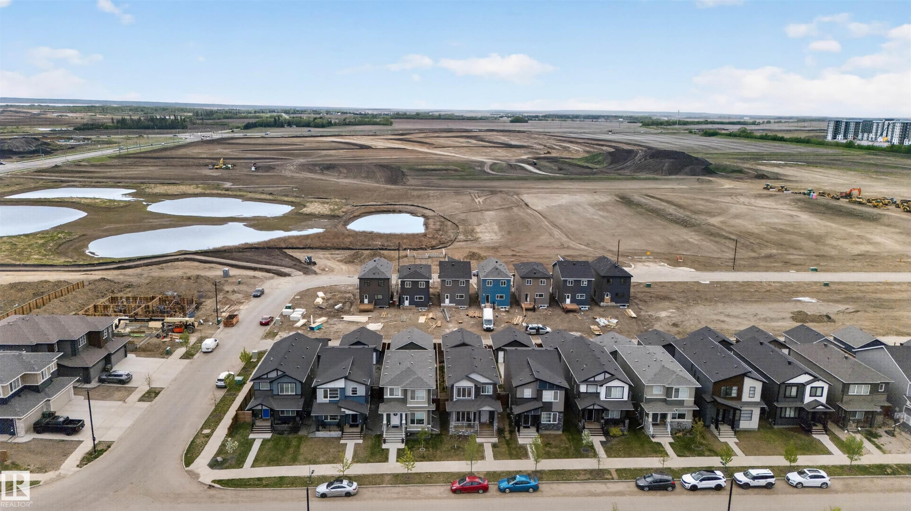 Residential street with a row of detached homes featuring varied exterior finishes and attached garages - 45 River Birch, St. Albert, AB - Outdoor With View