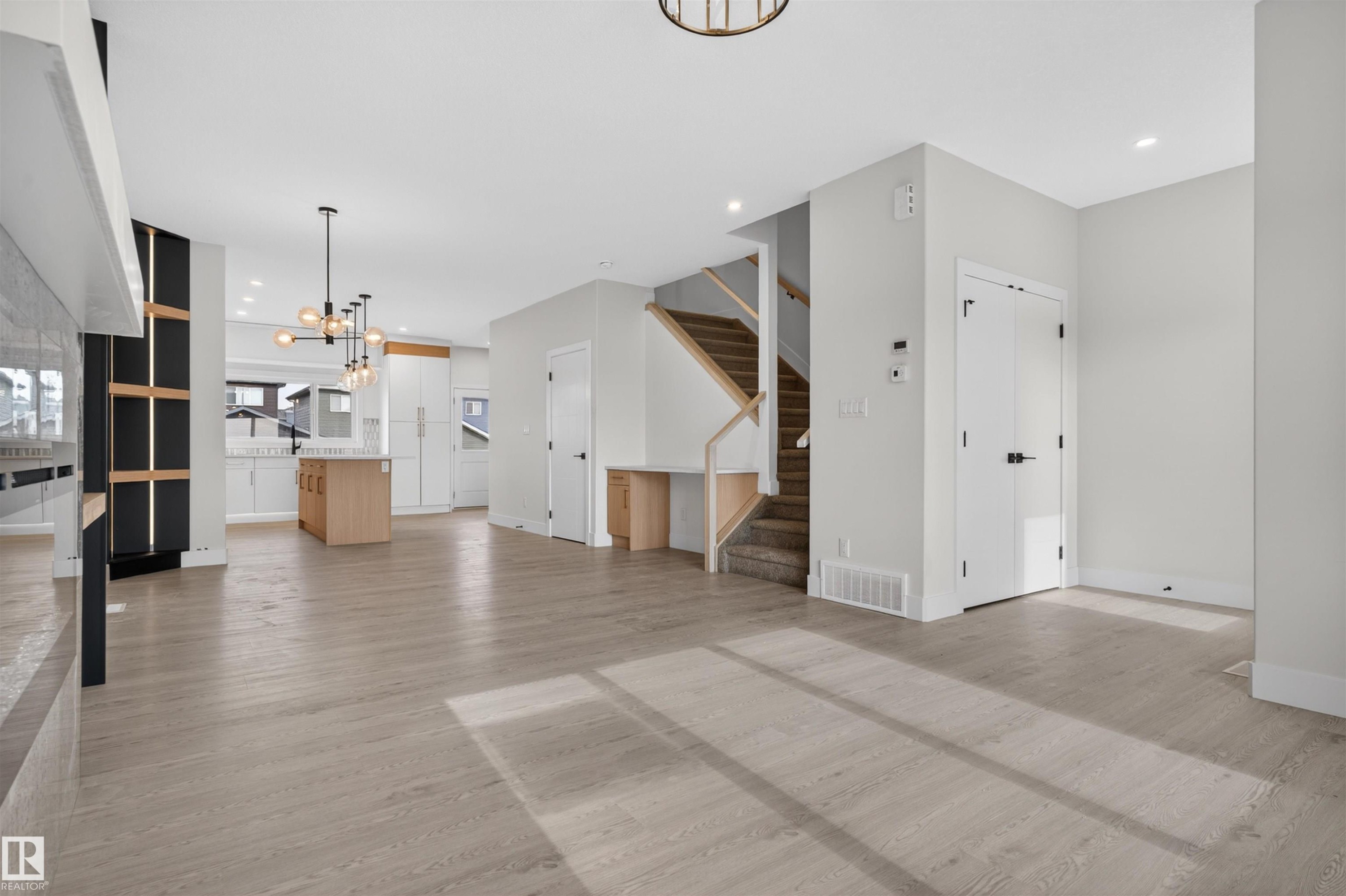 Expansive open-concept living area featuring wood-finish flooring, recessed lighting, and a modern chandelier - 45 River Birch, St. Albert, AB - Indoor