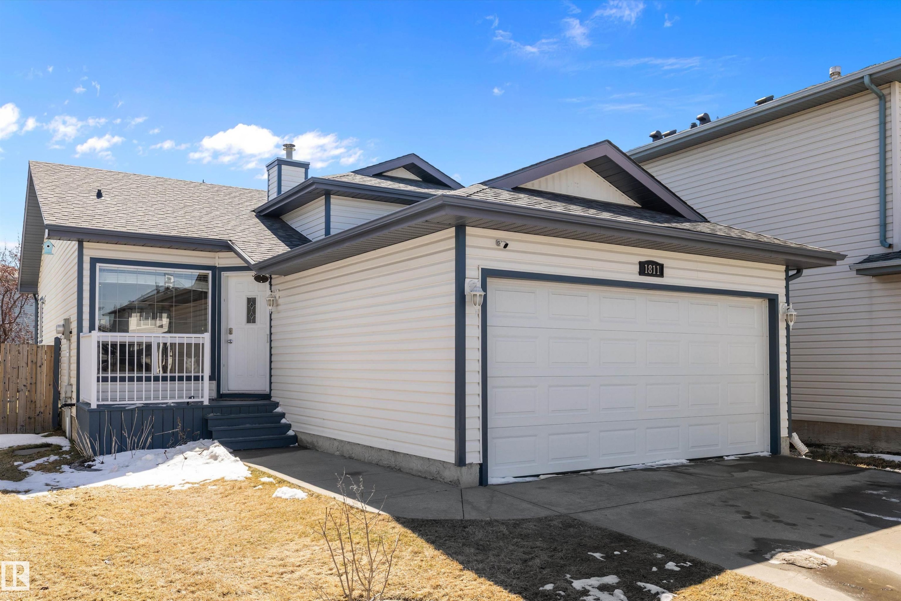Contemporary exterior featuring white siding with dark trim accents, an attached garage, a covered front porch with white railings, a prominent front window, and a gabled roofline - 1811 37 Avenue, Edmonton, AB - Outdoor With Deck Patio Veranda With Exterior