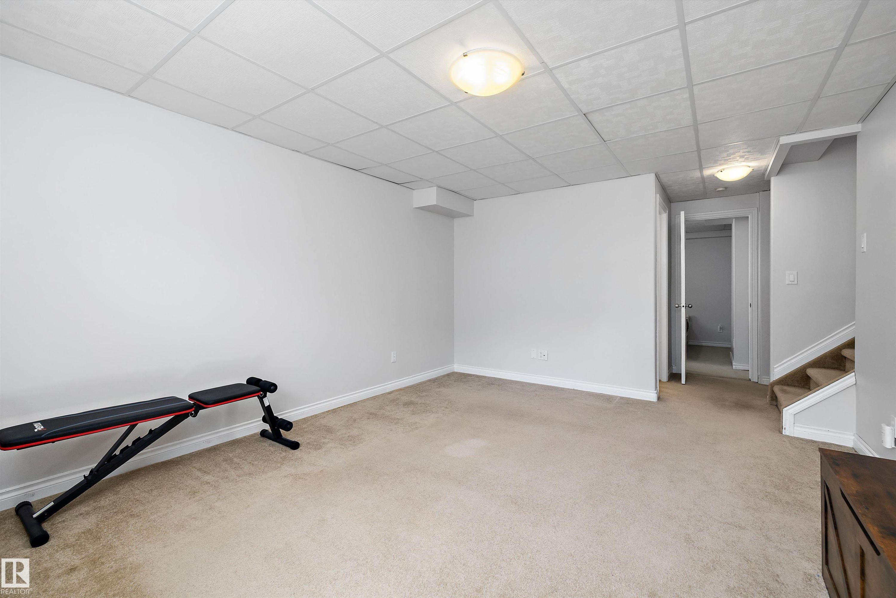 Finished room featuring light-toned carpeting, neutral painted walls, and a drop ceiling with integrated flush-mount lighting - 1811 37 Avenue, Edmonton, AB - Indoor Photo Showing Gym Room