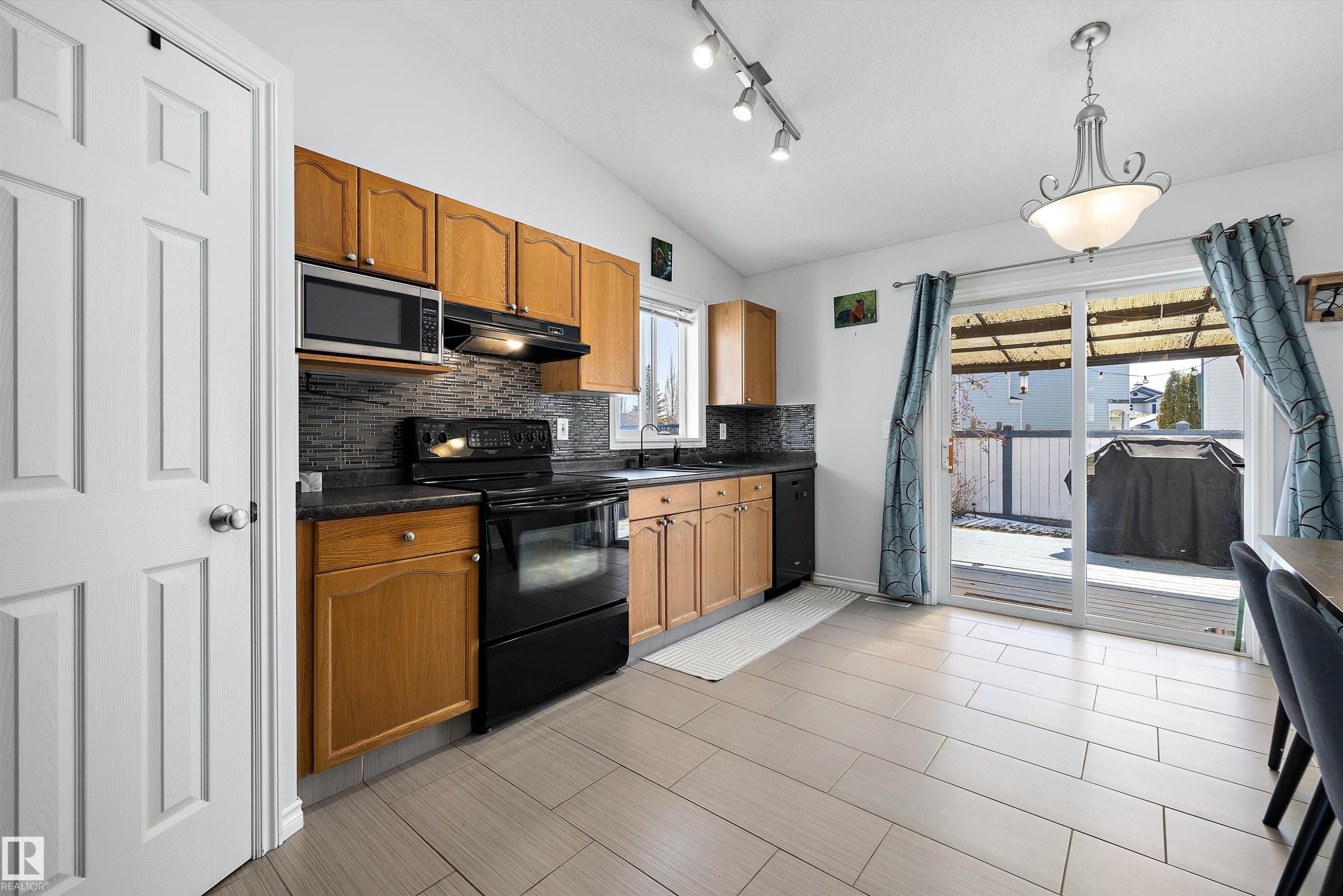 Kitchen featuring wood cabinetry, dark countertops, and a full suite of black appliances - 1811 37 Avenue, Edmonton, AB - Indoor Photo Showing Kitchen