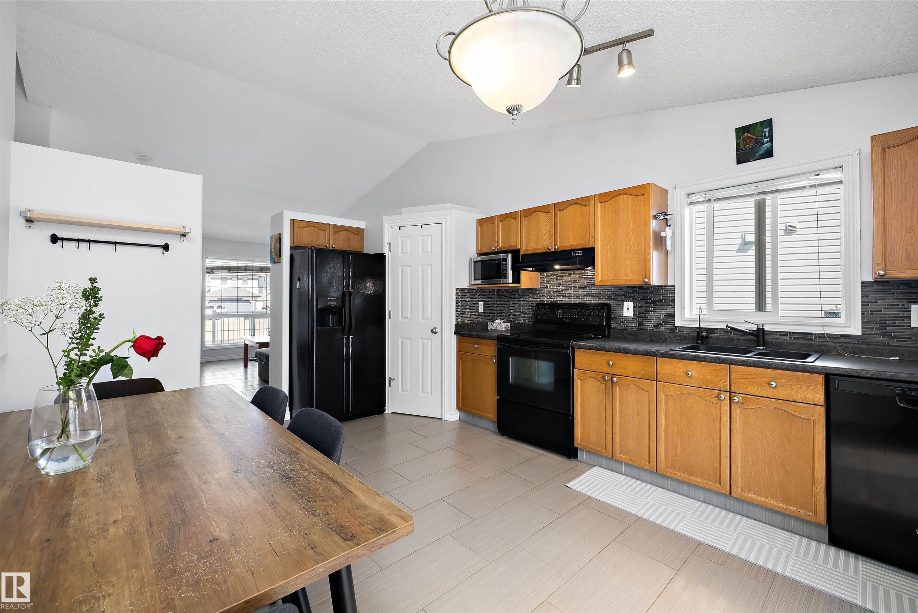 Kitchen featuring wood cabinetry, dark countertops, and a tiled backsplash - 1811 37 Avenue, Edmonton, AB - Indoor Photo Showing Kitchen With Double Sink