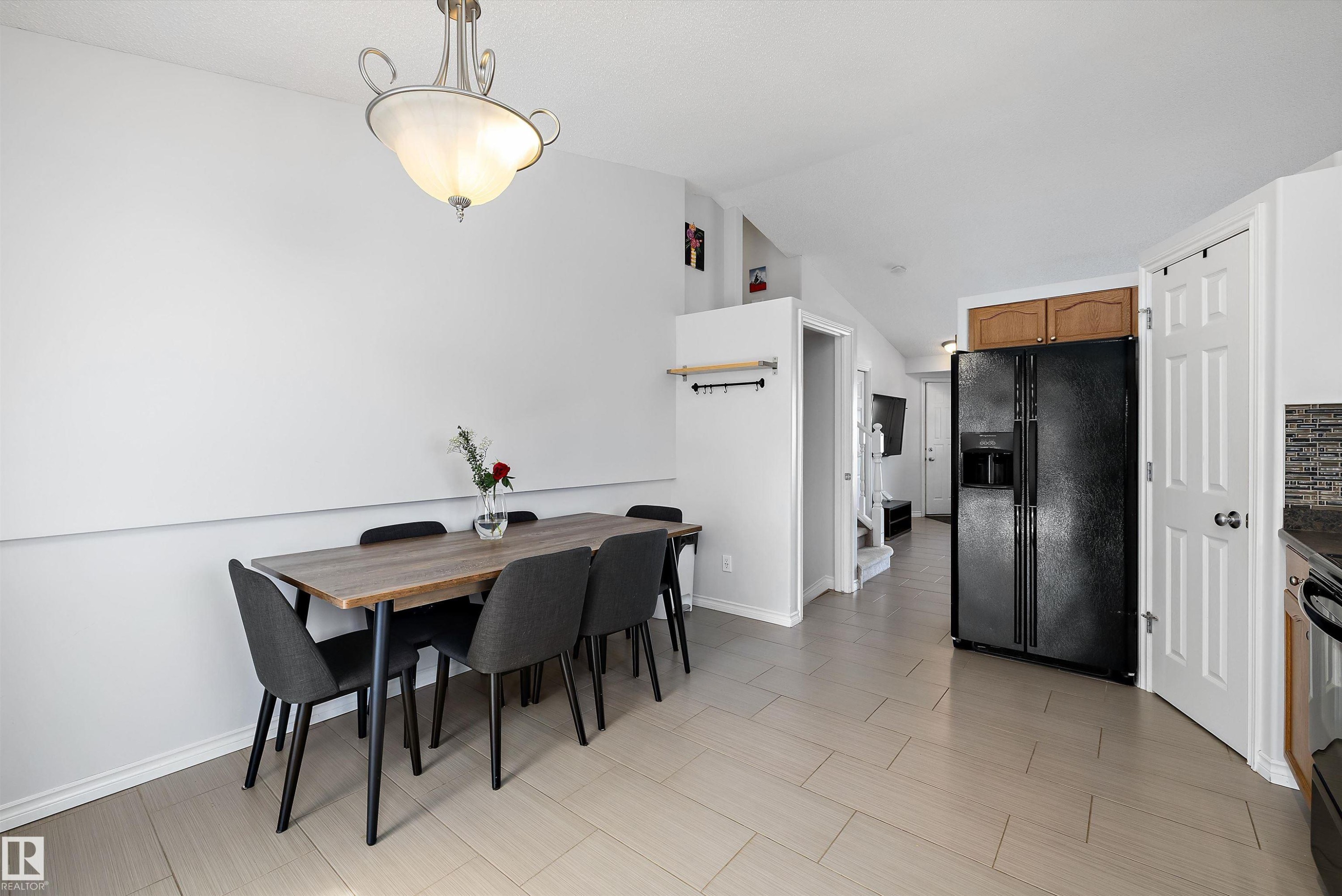 Open concept dining area with light-toned rectangular tile flooring, featuring a contemporary ceiling light fixture - 1811 37 Avenue, Edmonton, AB - Indoor