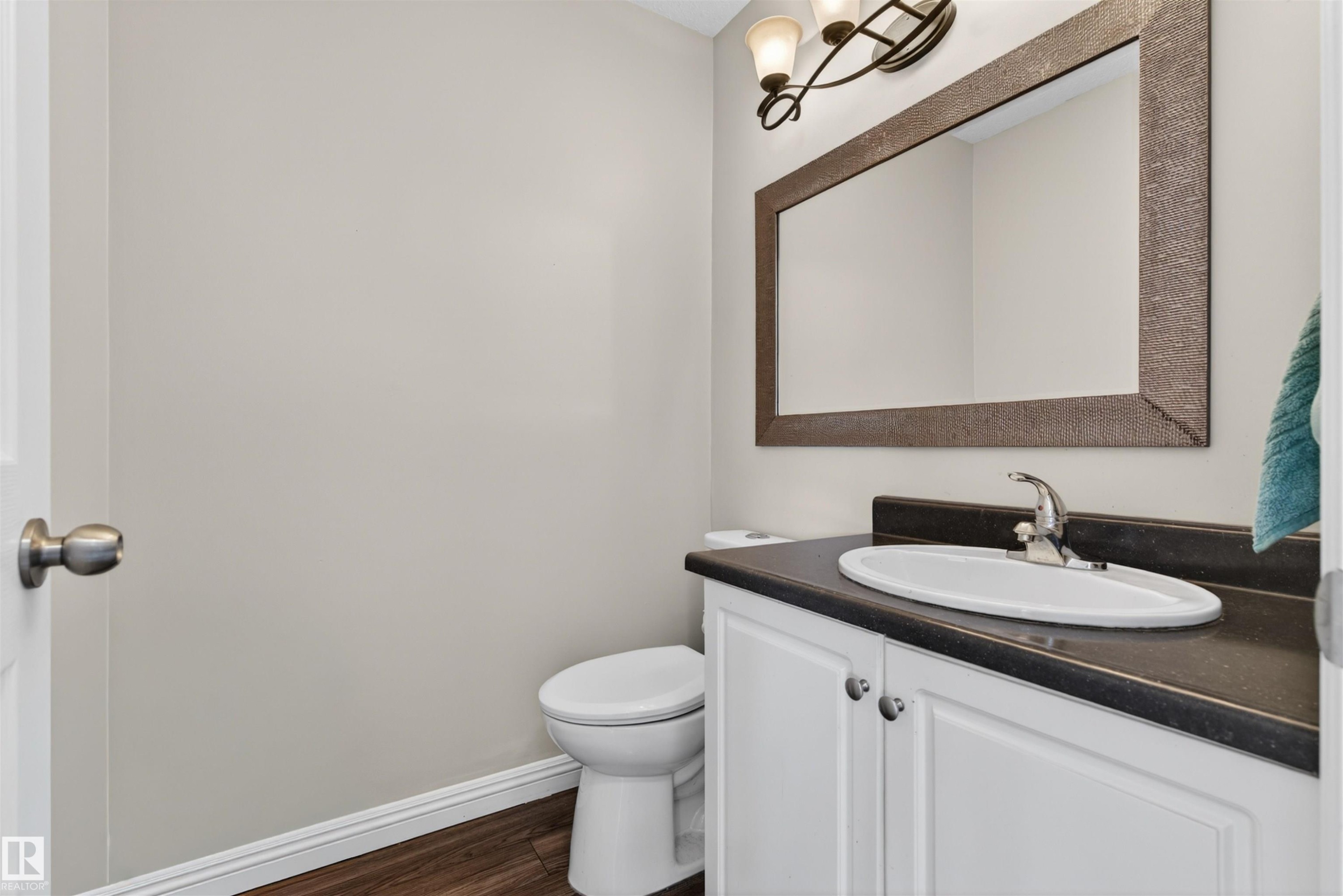 Bathroom featuring a vanity with white cabinetry, a dark countertop, an oval sink, and a rectangular framed mirror with an overhead light fixture - 2 Sturgeon Road, St. Albert, AB - Indoor Photo Showing Bathroom