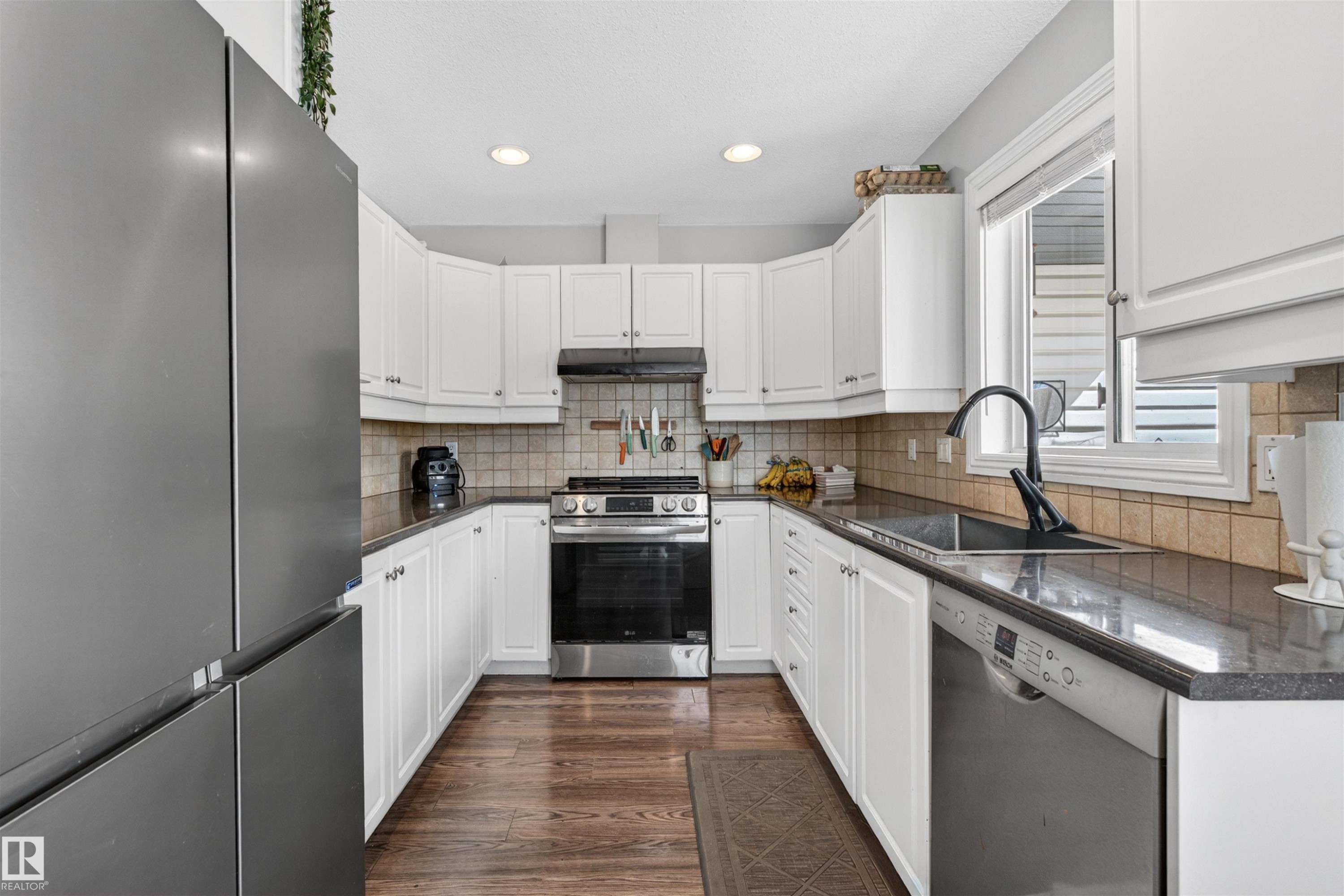 The kitchen features white cabinetry, dark countertops, a stainless steel oven and range, and a window above the sink - 2 Sturgeon Road, St. Albert, AB - Indoor Photo Showing Kitchen With Upgraded Kitchen