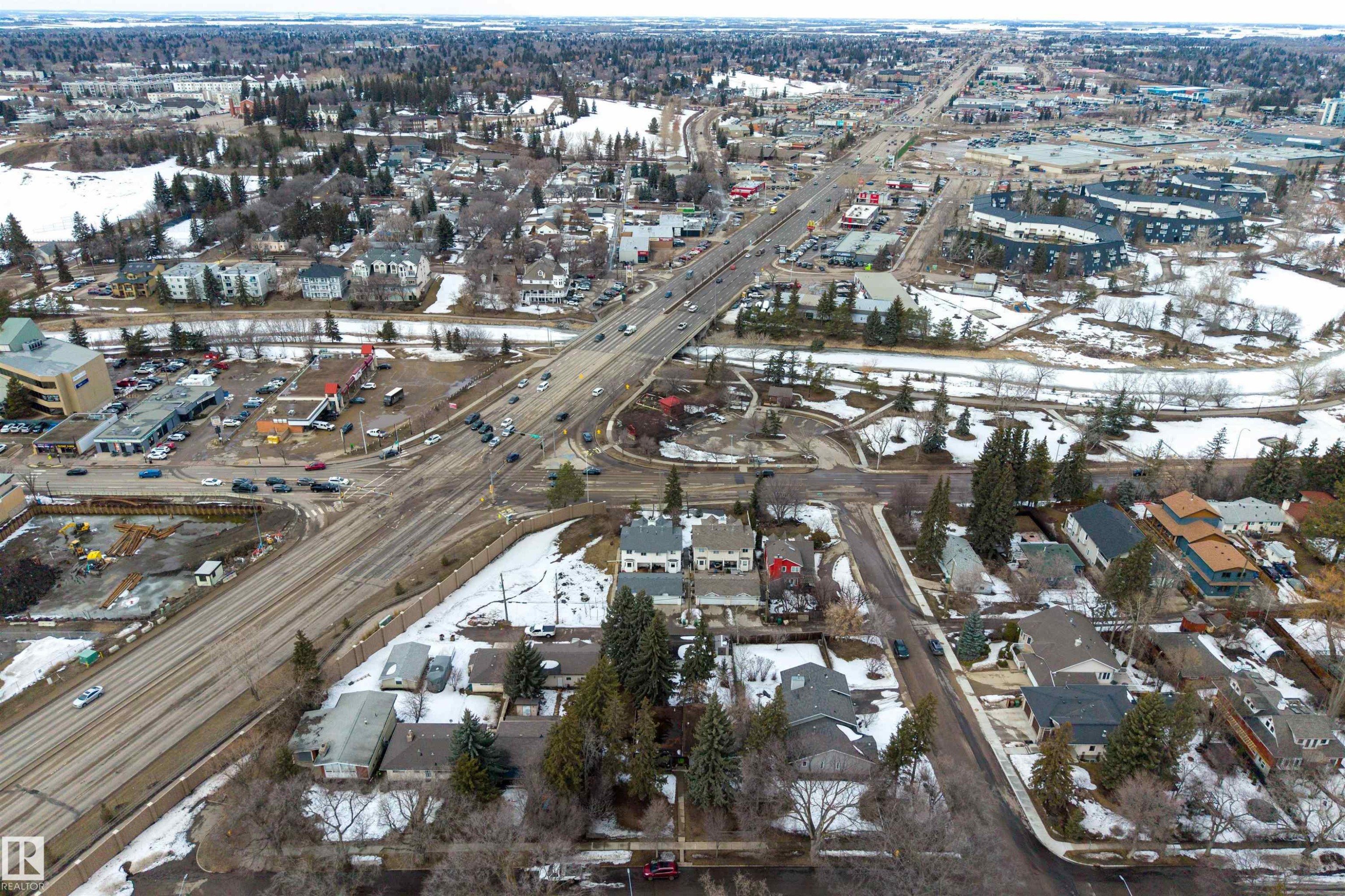 Aerial view showcasing the surrounding neighborhood, featuring residential properties, commercial buildings, and a thoroughfare with vehicular movement - 2 Sturgeon Road, St. Albert, AB - Outdoor With View