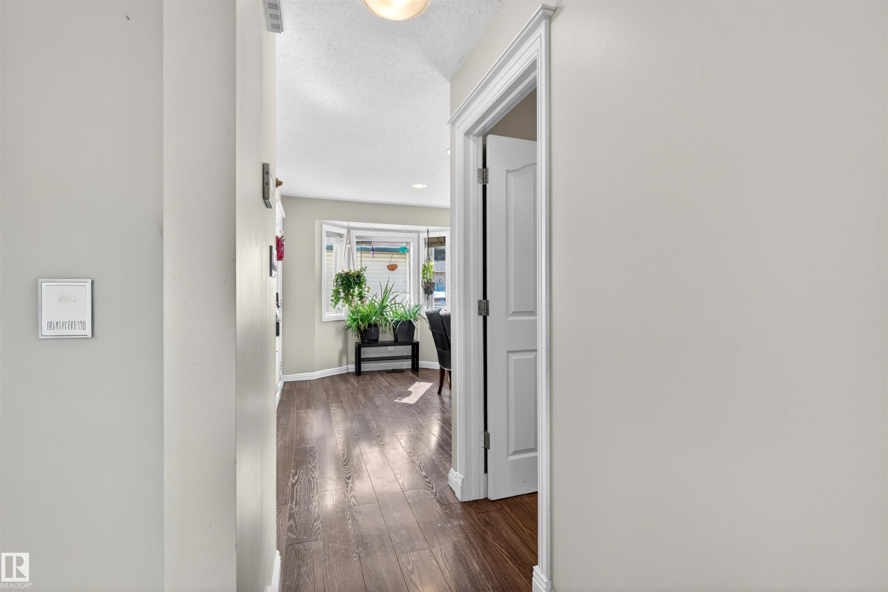 Hallway with dark hardwood flooring and light-colored walls leading to a bright living area - 2 Sturgeon Road, St. Albert, AB - Indoor Photo Showing Other Room