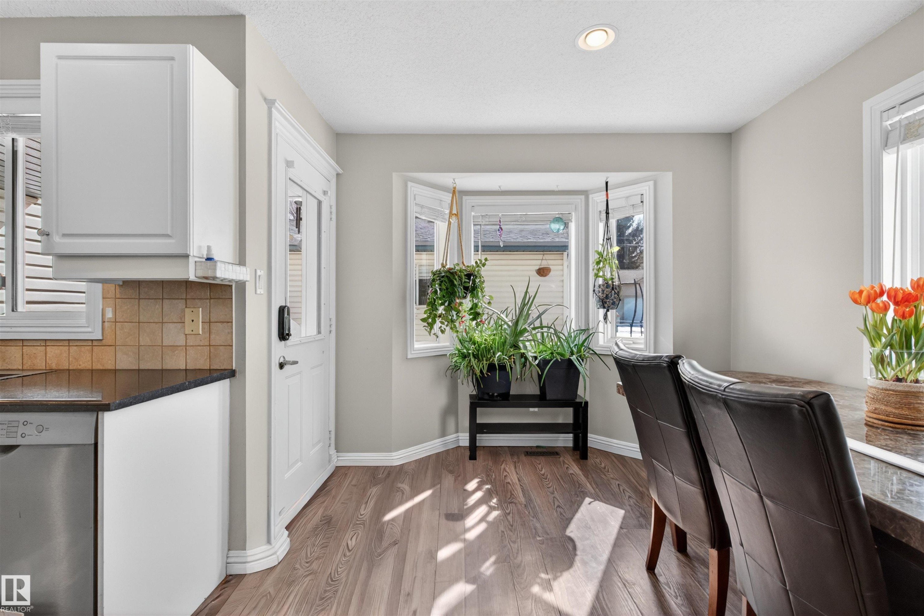 The property features a kitchen area with white cabinetry, a tiled backsplash, and a stainless steel dishwasher - 2 Sturgeon Road, St. Albert, AB - Indoor