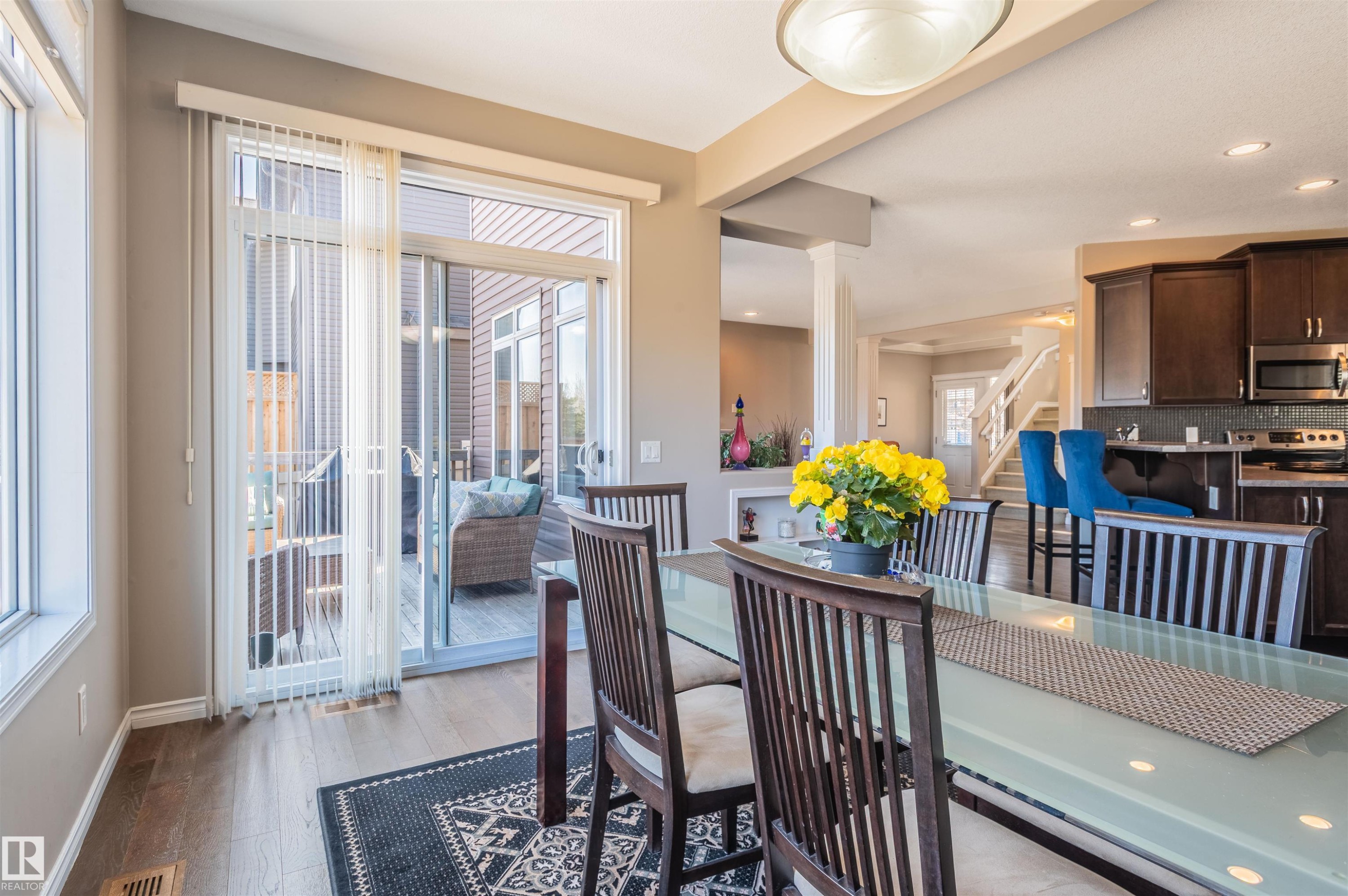 Dining area featuring wood-finish flooring, a glass-top dining table, and direct access to an outdoor deck - 121 Ellington Crescent, St. Albert, AB - Indoor Photo Showing Dining Room