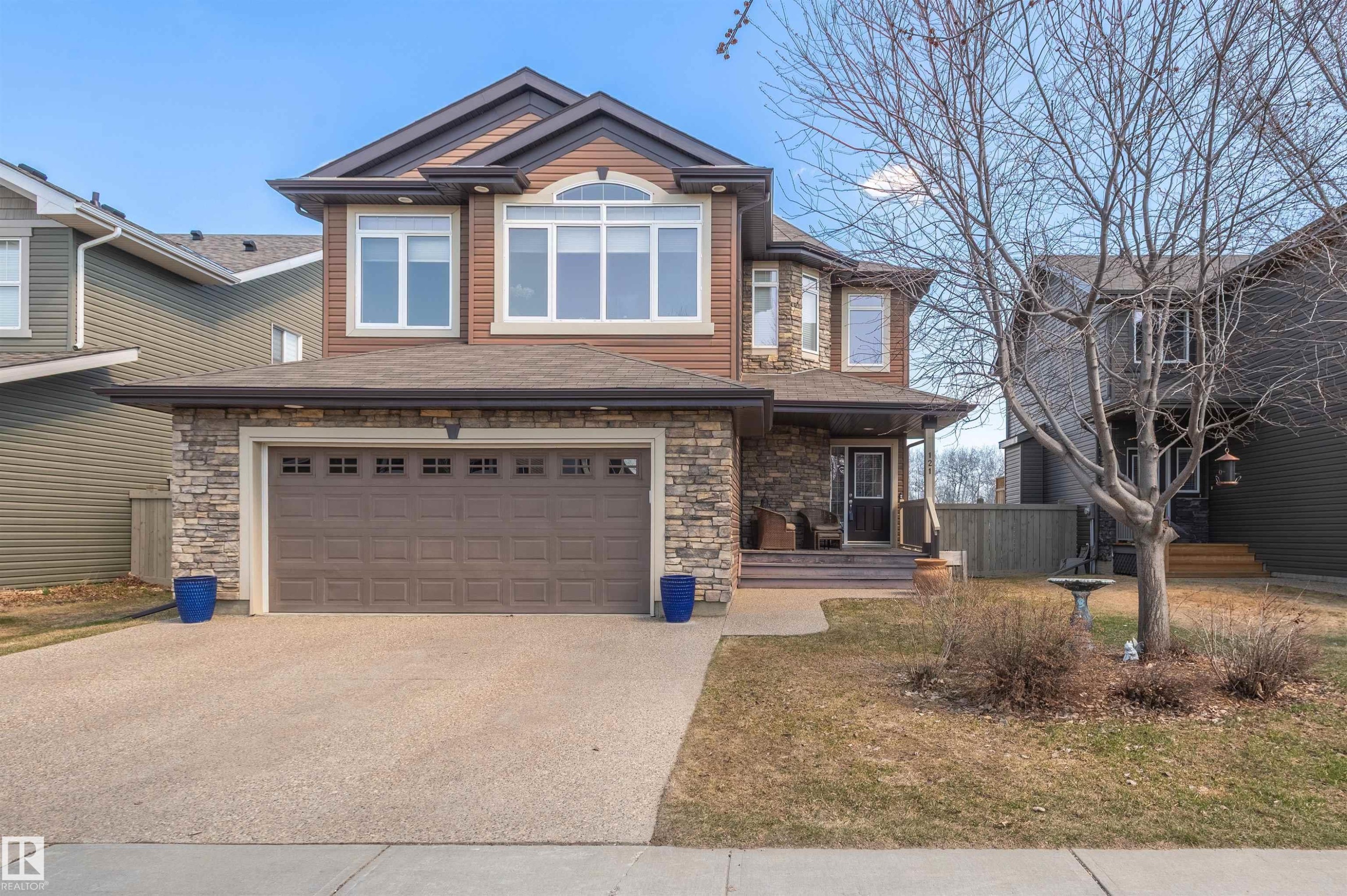Two-story residence featuring a brown siding exterior, a stone-clad first level, and a covered front porch - 121 Ellington Crescent, St. Albert, AB - Outdoor With Facade