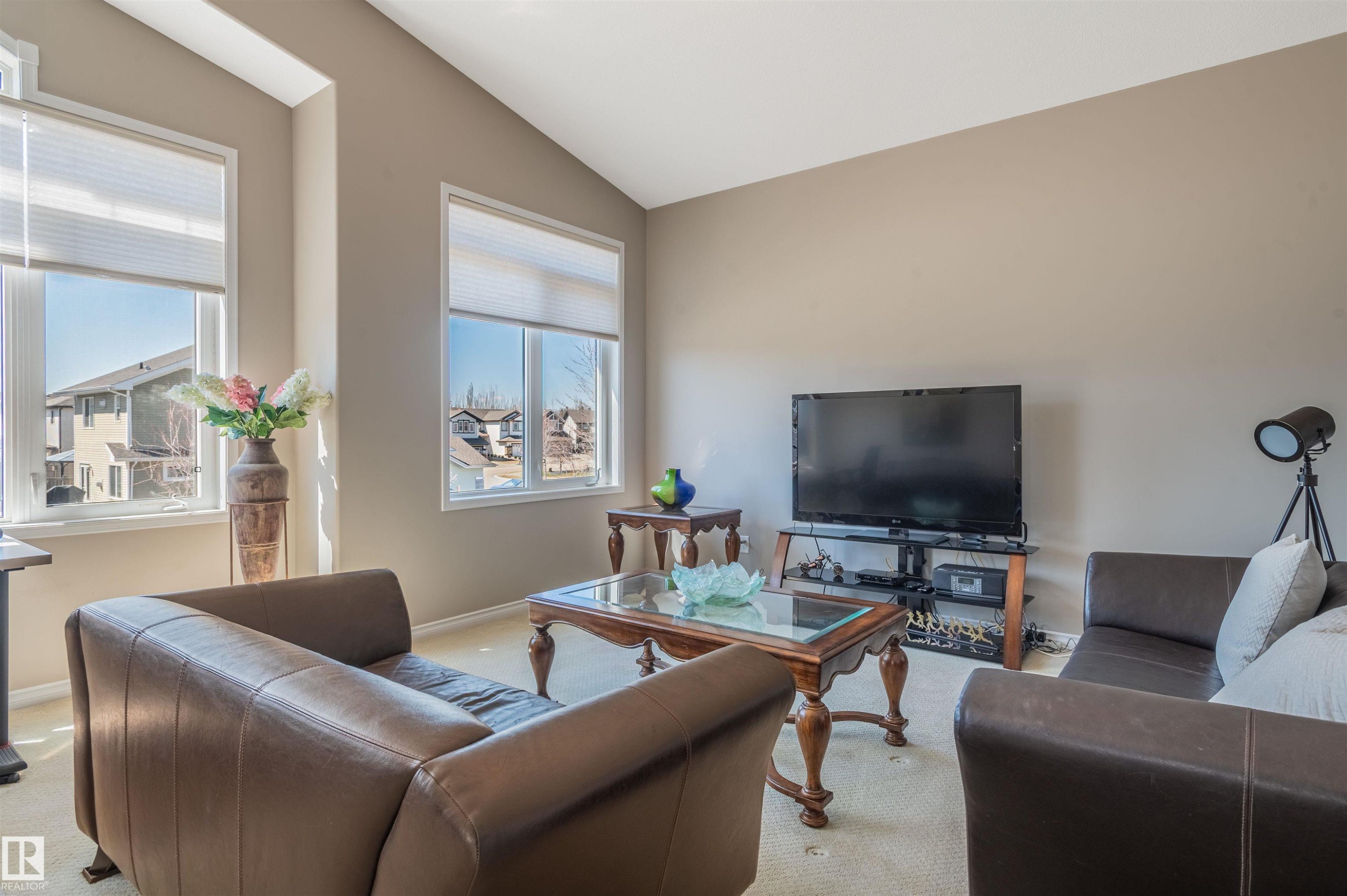 Vaulted ceilings elevate this living area, featuring multiple windows with blinds, neutral wall tones, and light-toned carpeting - 121 Ellington Crescent, St. Albert, AB - Indoor Photo Showing Living Room
