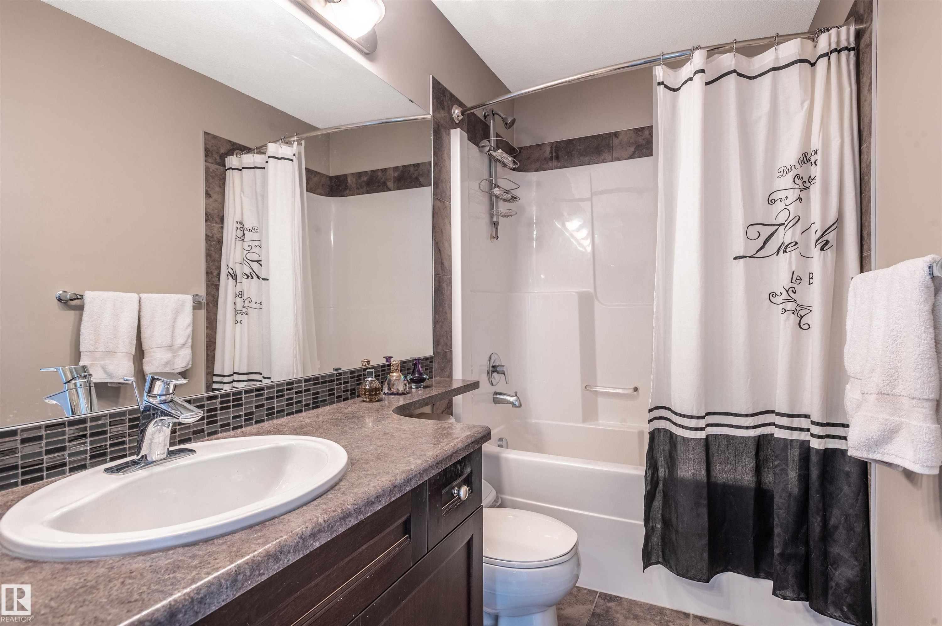 Bathroom featuring a single vanity with an integrated sink, dark wood cabinetry, and a stone-finish countertop - 121 Ellington Crescent, St. Albert, AB - Indoor Photo Showing Bathroom