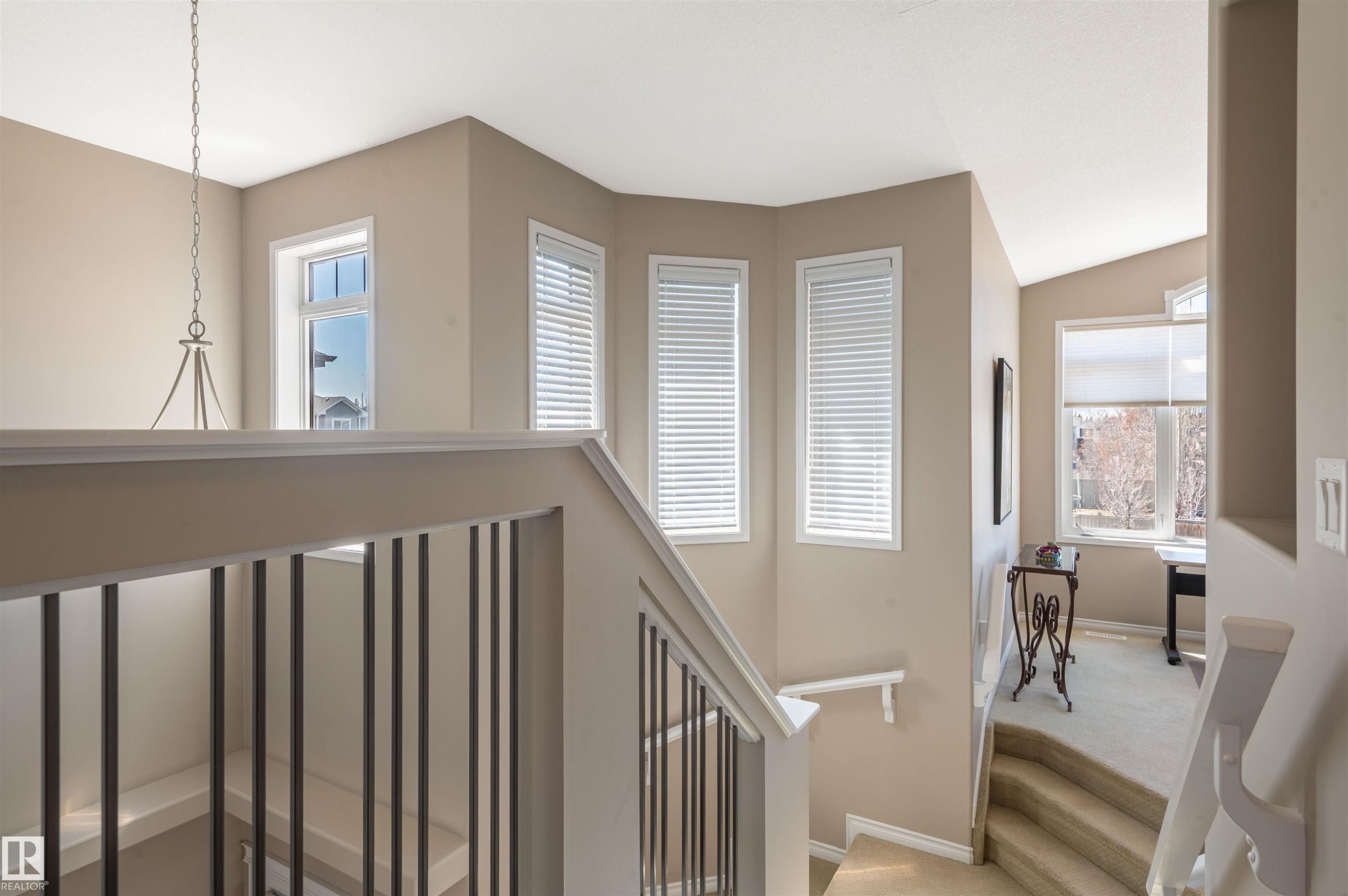 Open-concept upper landing featuring a wrought iron and wood banister, multiple large windows, and neutral wall tones - 121 Ellington Crescent, St. Albert, AB - Indoor Photo Showing Other Room