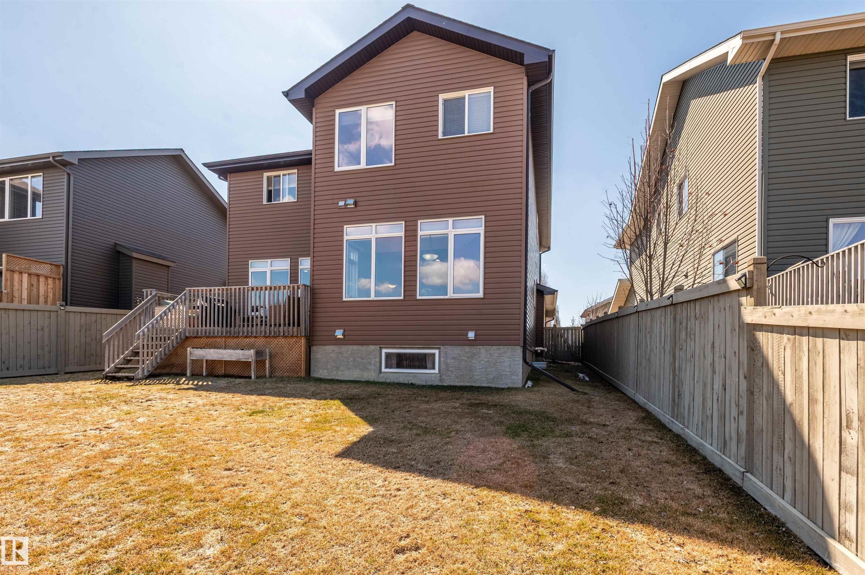 Brown vinyl siding exterior with an elevated wooden deck and stairs, fenced backyard, and multiple windows - 121 Ellington Crescent, St. Albert, AB - Outdoor With Deck Patio Veranda With Exterior