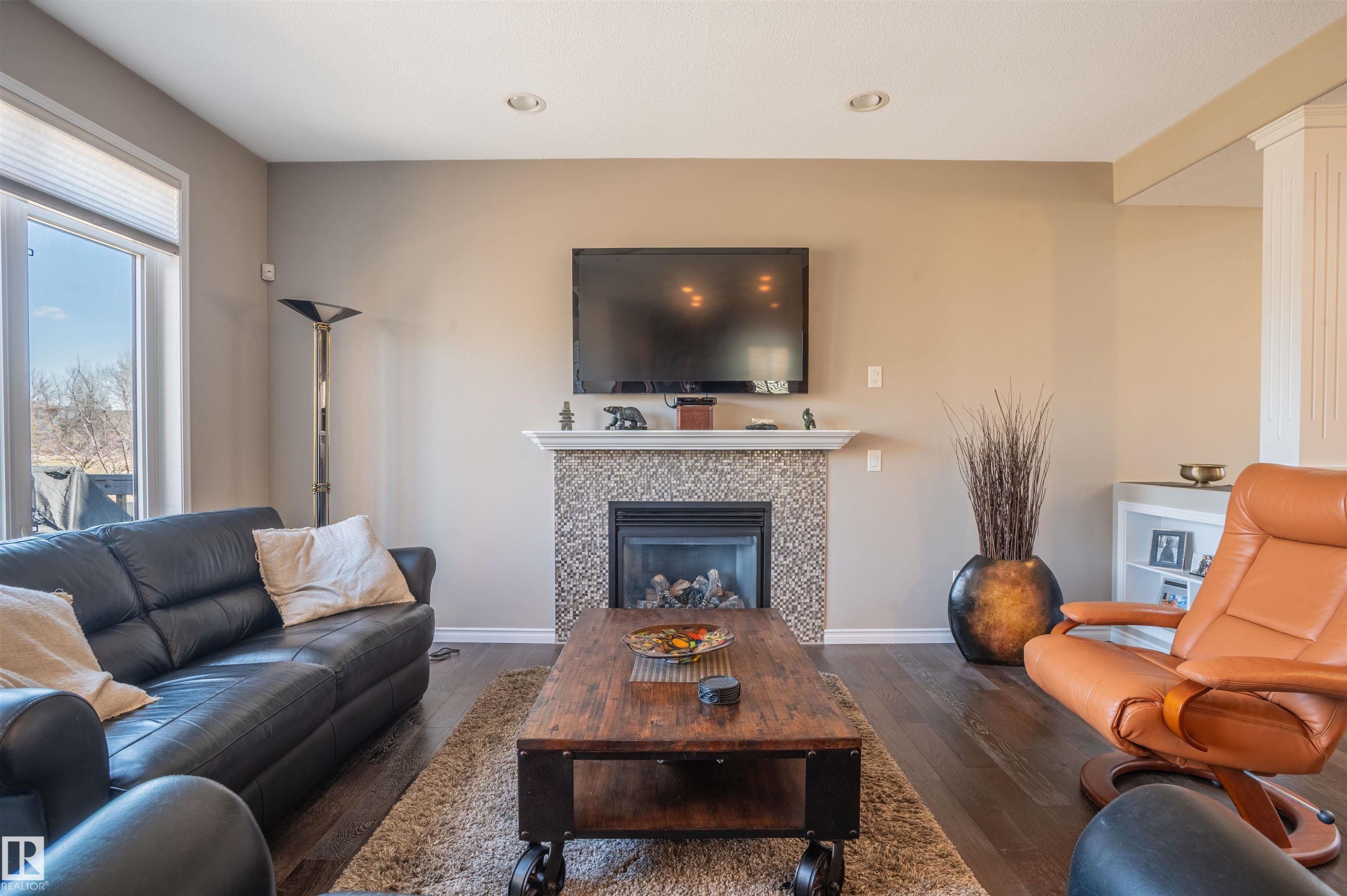 Living area featuring a fireplace with a mosaic tile surround and white mantle, dark wood-finish flooring, and recessed lighting - 121 Ellington Crescent, St. Albert, AB - Indoor Photo Showing Living Room With Fireplace