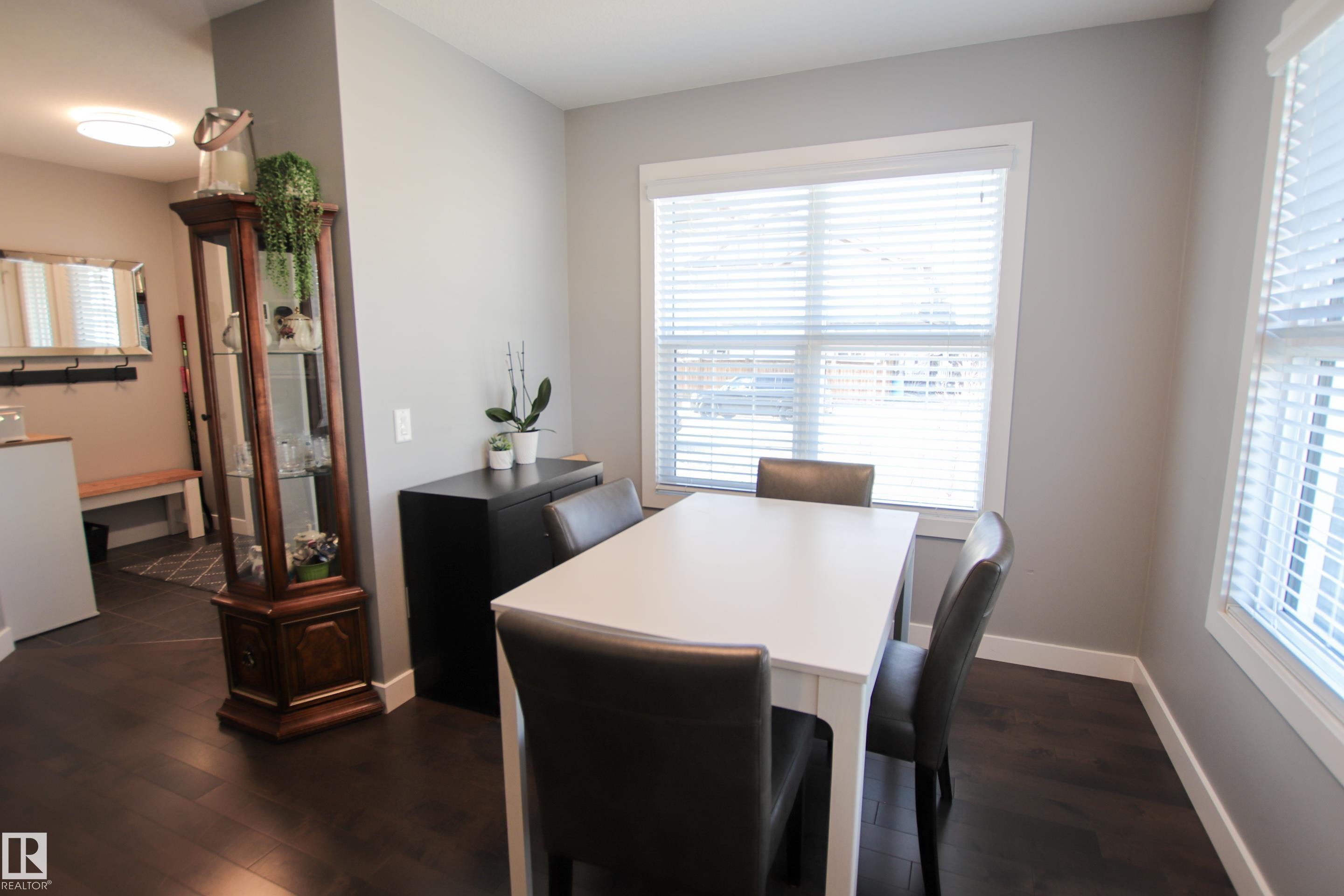 Spacious dining area featuring dark wood-finish flooring, light grey painted walls, and abundant natural light from multiple windows - 3805 170A Avenue, Edmonton, AB - Indoor Photo Showing Dining Room