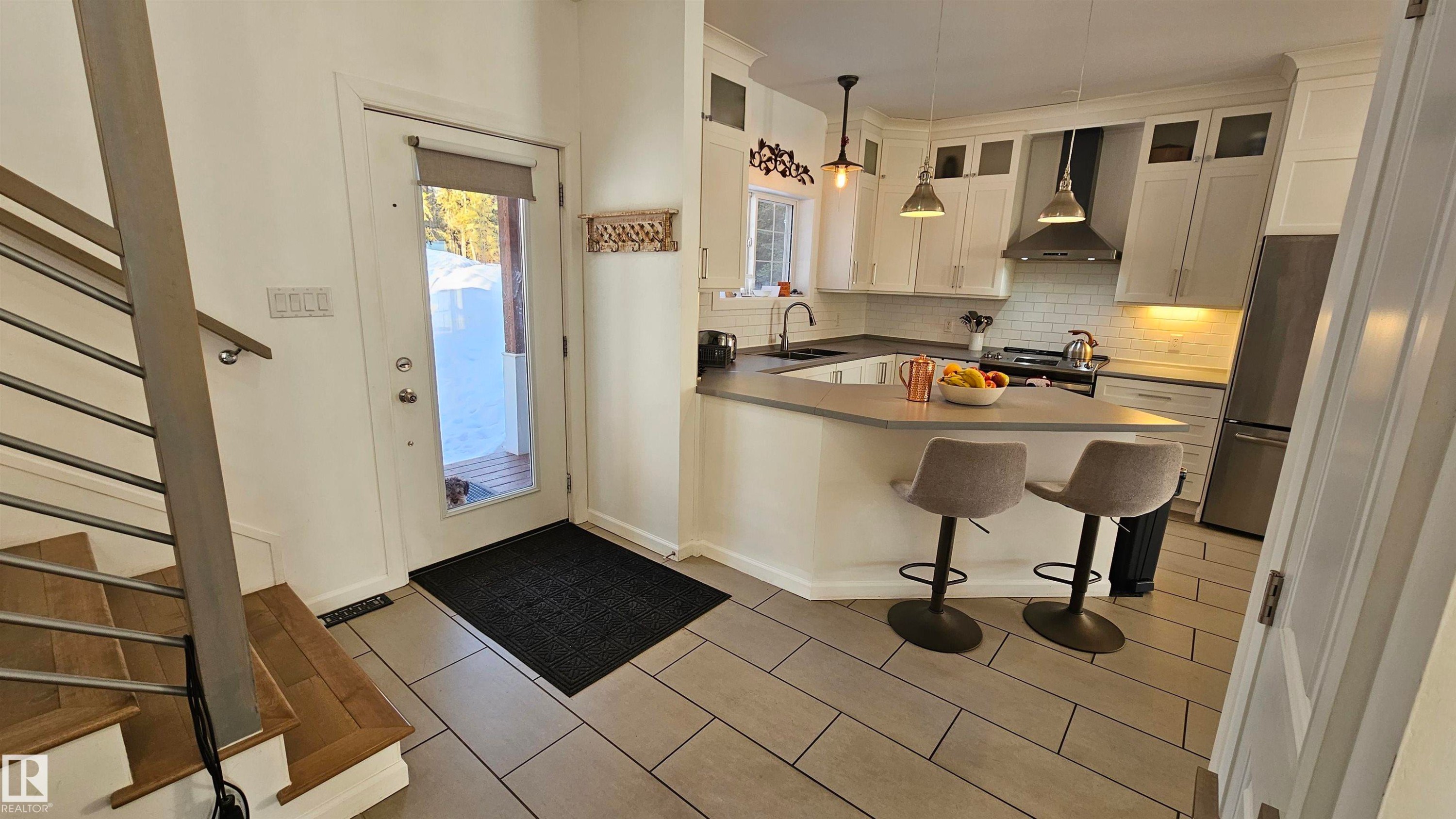 Kitchen featuring stainless steel appliances, tasteful backsplash, pendant lighting, a breakfast bar, and a peninsula - 58513 Range Road 231, Rural Thorhild County, AB - Indoor Photo Showing Kitchen With Double Sink