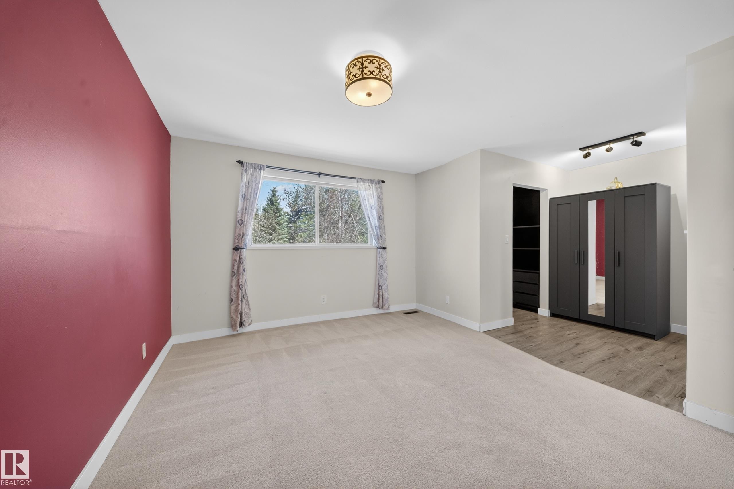 Spacious room featuring a large window, neutral carpeting, and a contrasting accent wall - 1767 61 Street, Edmonton, AB - Indoor Photo Showing Other Room