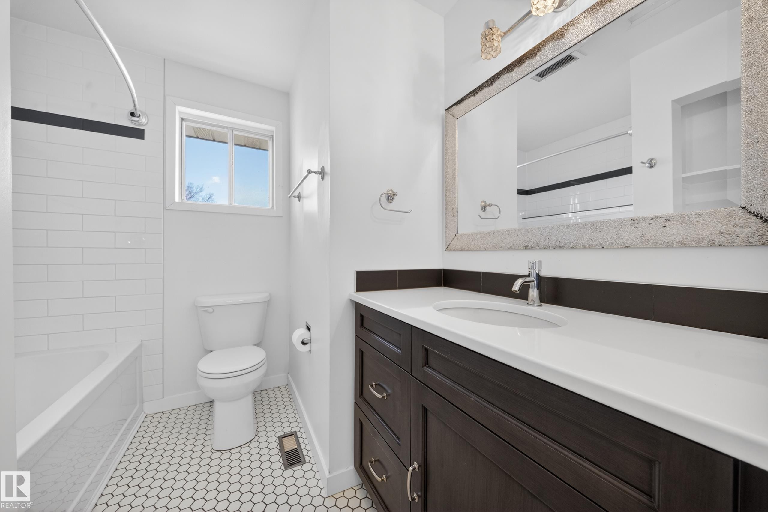 Bathroom with a dark wood-finish vanity, white countertop, and integrated sink - 1767 61 Street, Edmonton, AB - Indoor Photo Showing Bathroom