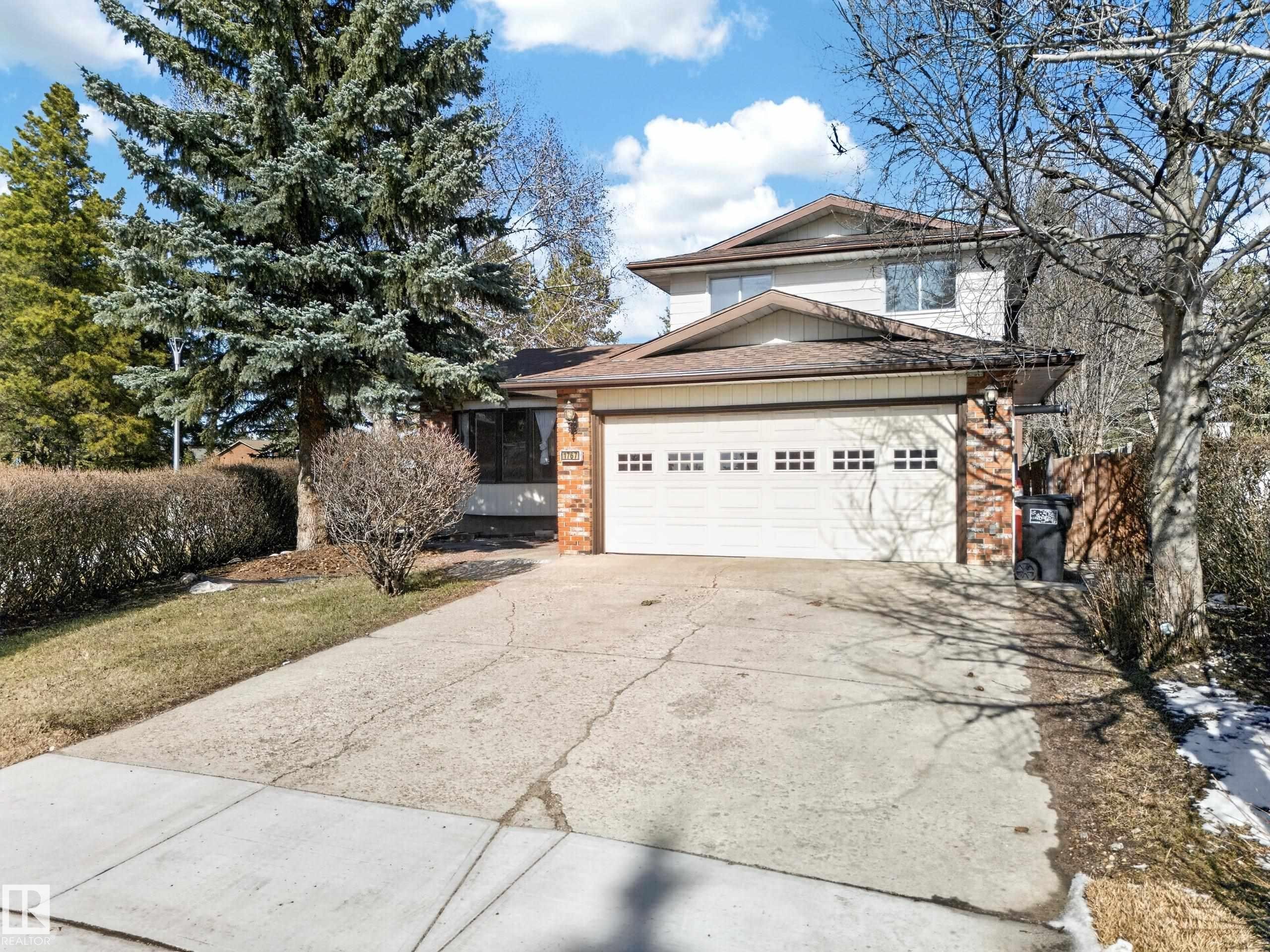 Two-story residence featuring a two-car garage with panel windows, a concrete driveway, and brick accents - 1767 61 Street, Edmonton, AB - Outdoor