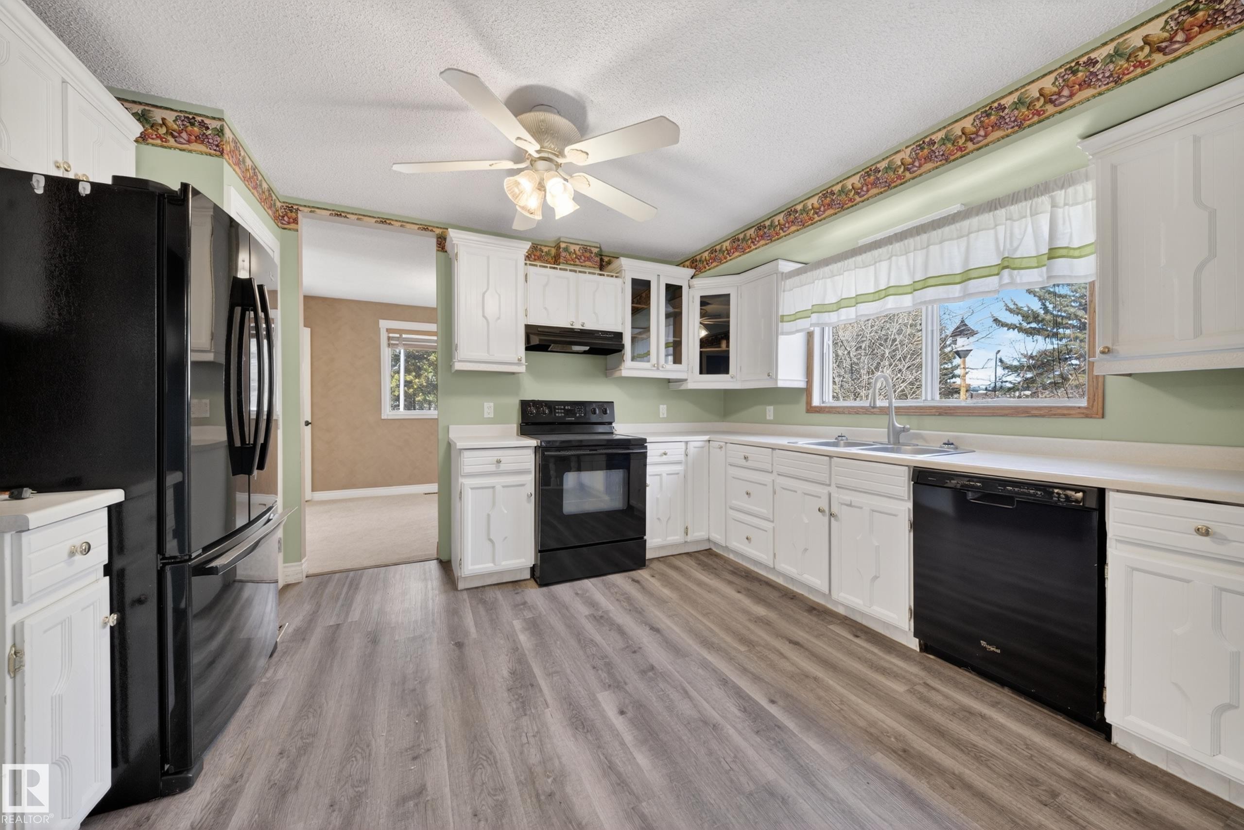 Kitchen featuring wood-finish flooring, white cabinetry, a double basin sink, and black appliances - 1767 61 Street, Edmonton, AB - Indoor Photo Showing Kitchen