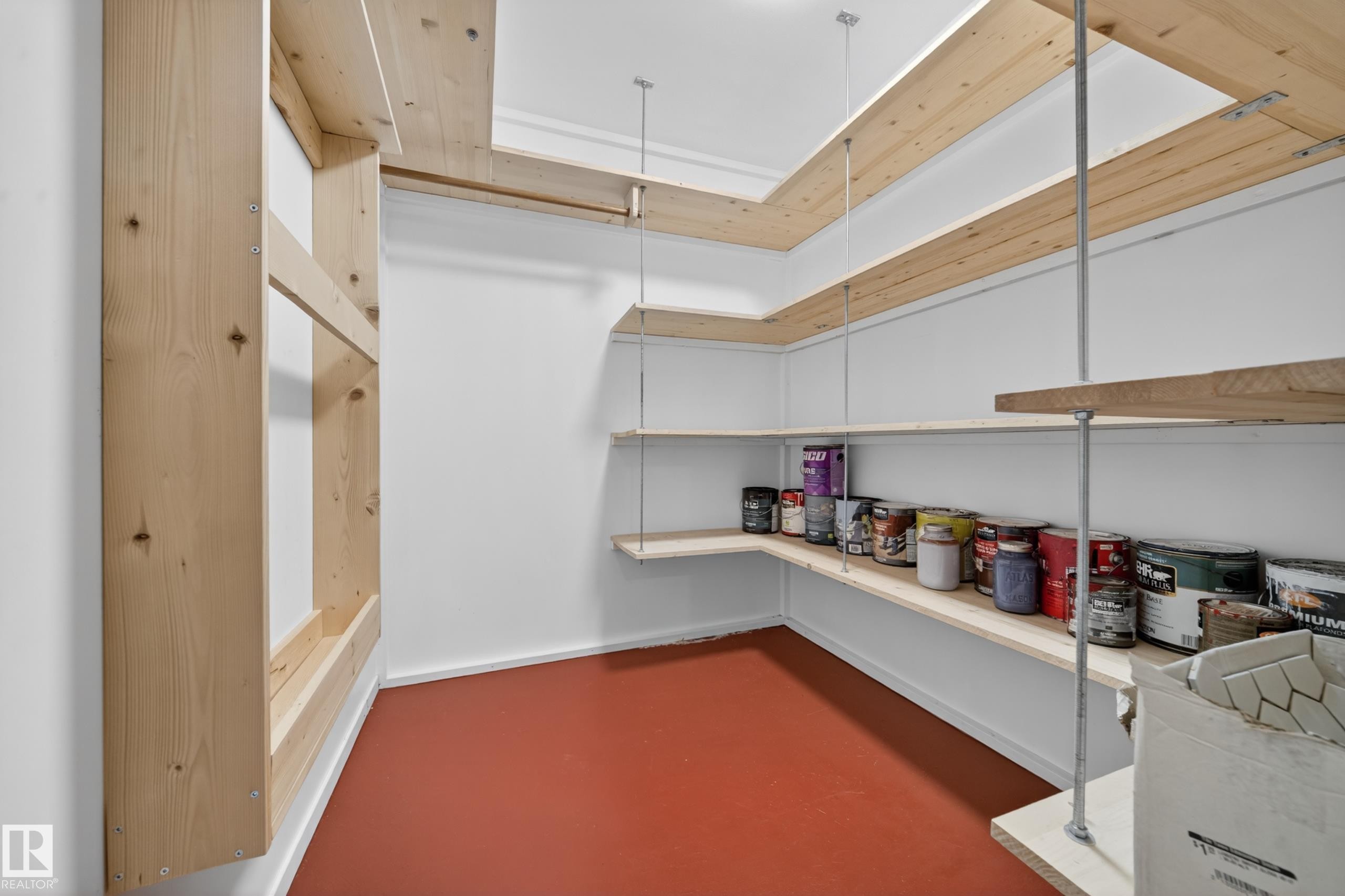 Spacious storage room featuring a resilient red floor, white walls, and extensive light wood shelving - 1767 61 Street, Edmonton, AB - Indoor