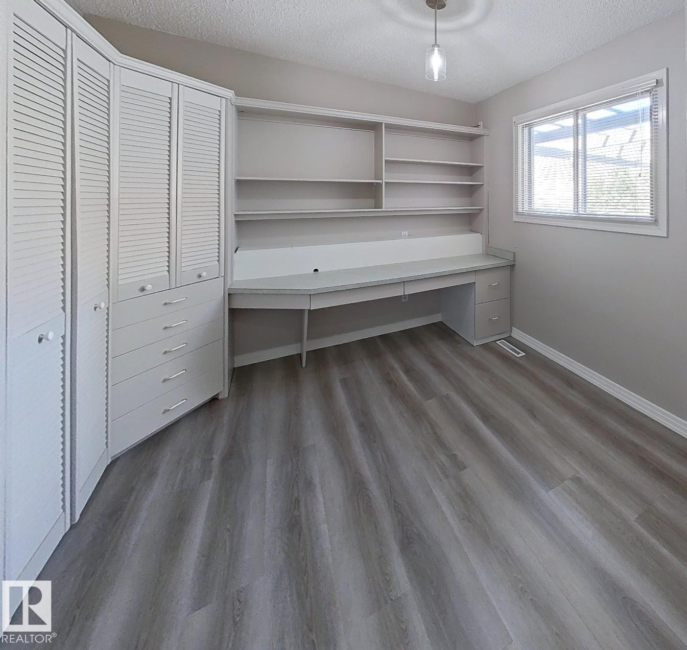 Built-in desk with shelving and integrated cabinetry featuring louvered doors - 9624 75 Street, Edmonton, AB - Indoor Photo Showing Other Room