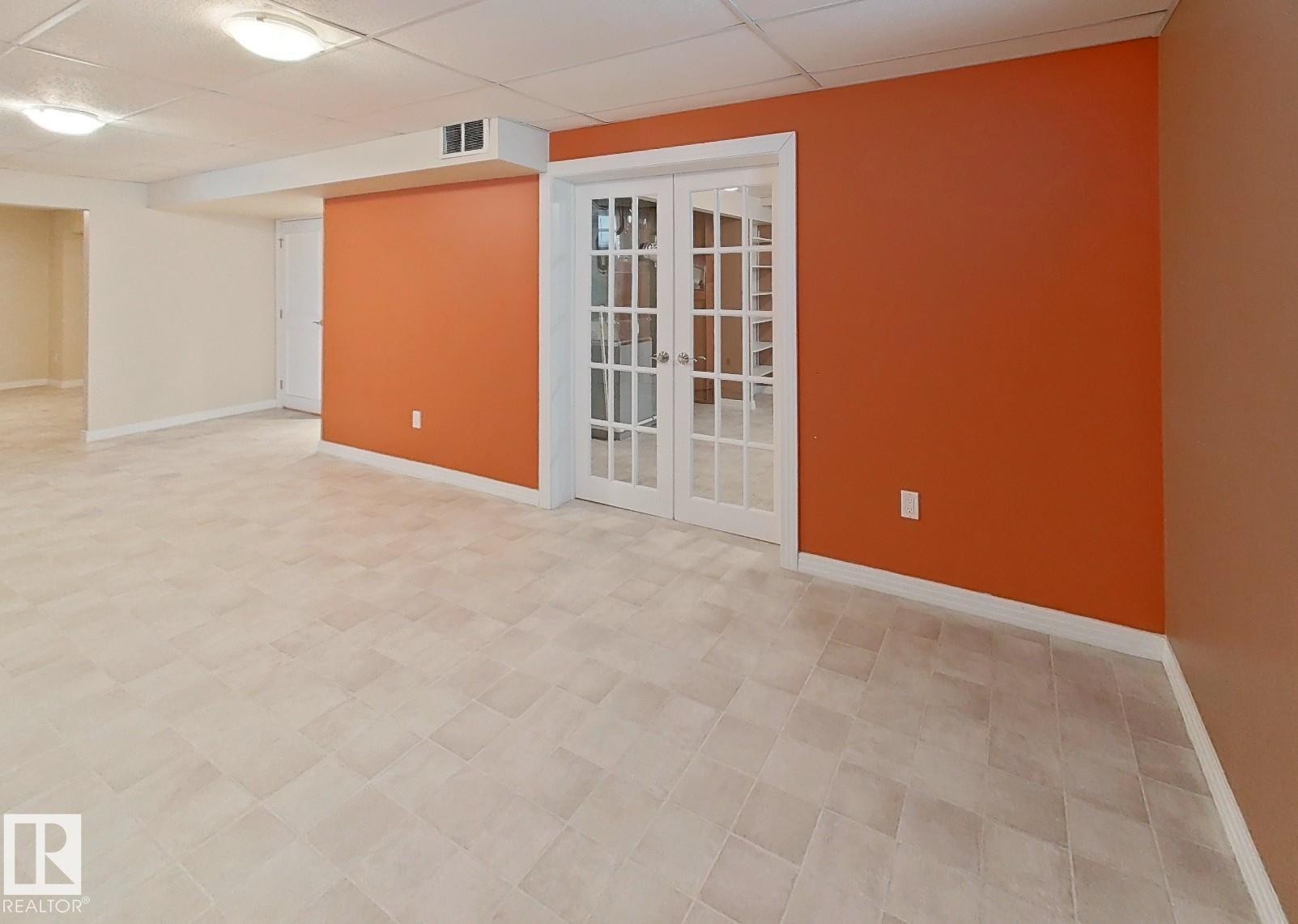 Finished lower level featuring light-toned square tile flooring, a drop ceiling with recessed lighting, and a vibrant accent wall - 9624 75 Street, Edmonton, AB - Indoor Photo Showing Other Room