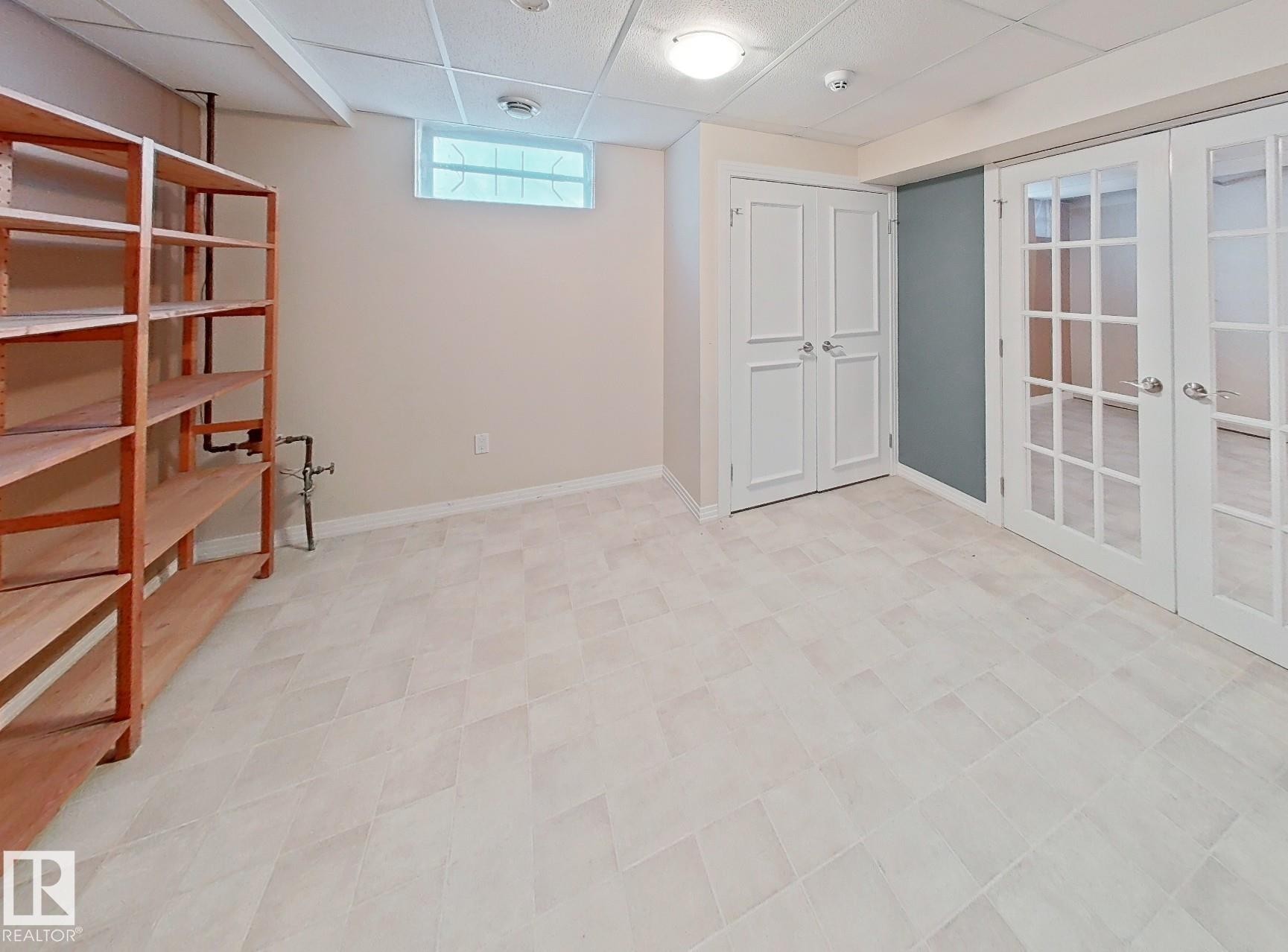 Spacious room with light-toned rectangular floor tiles, drop ceiling, and recessed lighting - 9624 75 Street, Edmonton, AB - Indoor