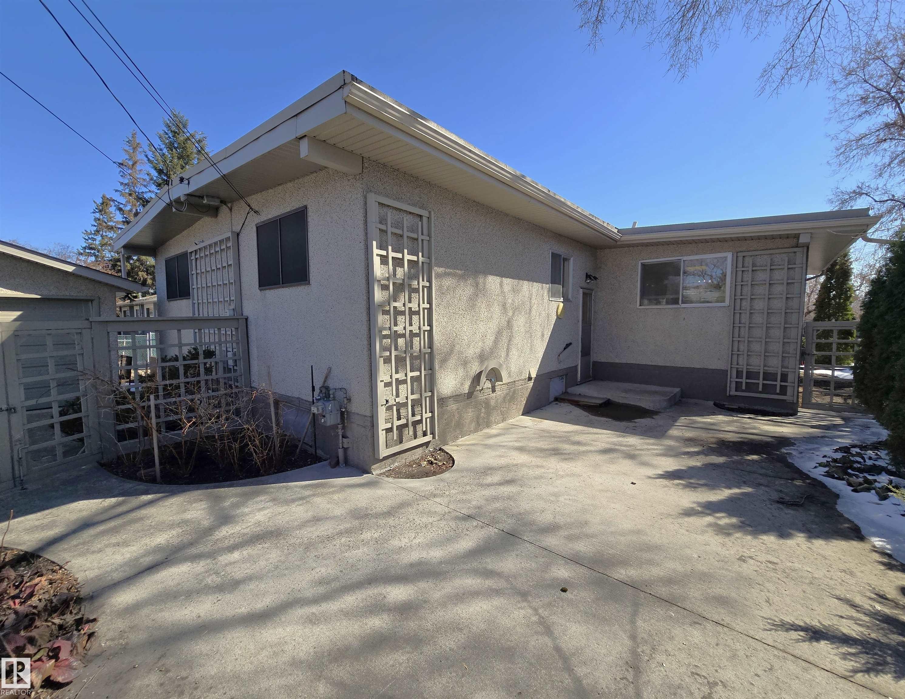 Expansive concrete patio with stucco exterior and lattice accents - 9624 75 Street, Edmonton, AB - Outdoor