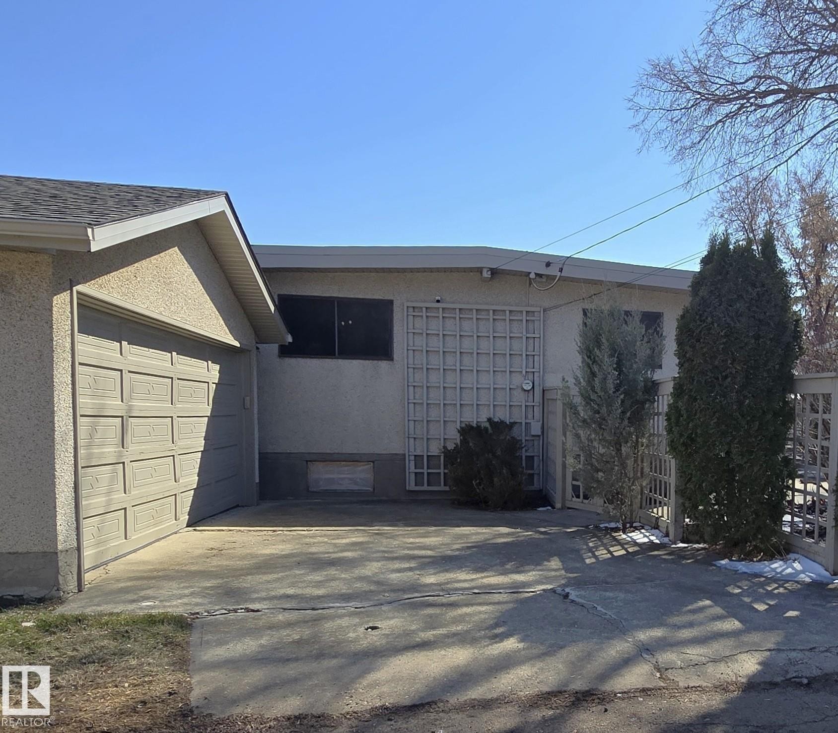 Attached single-car garage featuring a panel-style door and asphalt shingle roof - 9624 75 Street, Edmonton, AB - Outdoor