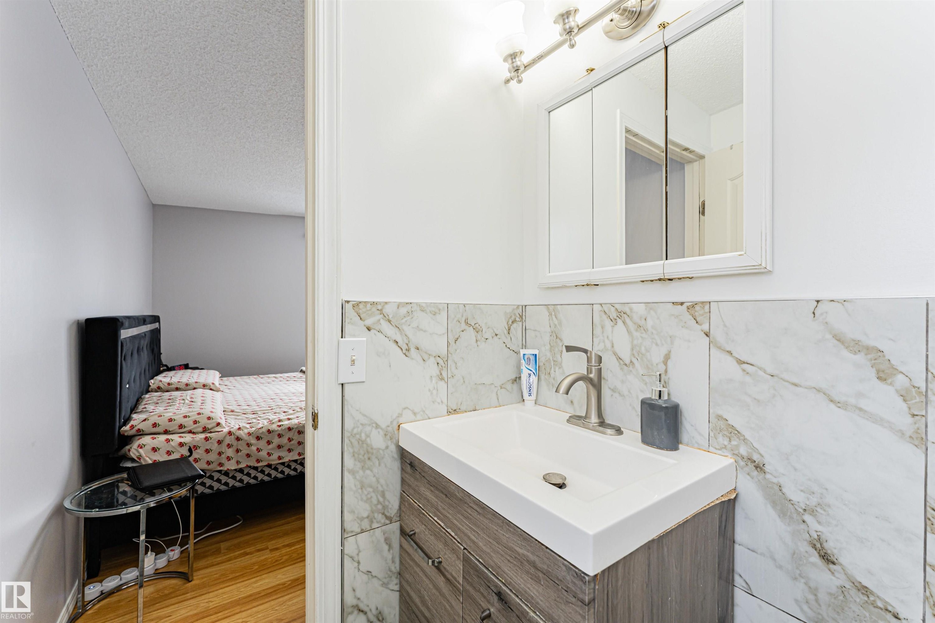 Bathroom featuring a vanity with a white sink, a brushed nickel faucet, and a medicine cabinet with an overhead light fixture - 10412 39 Avenue, Edmonton, AB - Indoor Photo Showing Bathroom