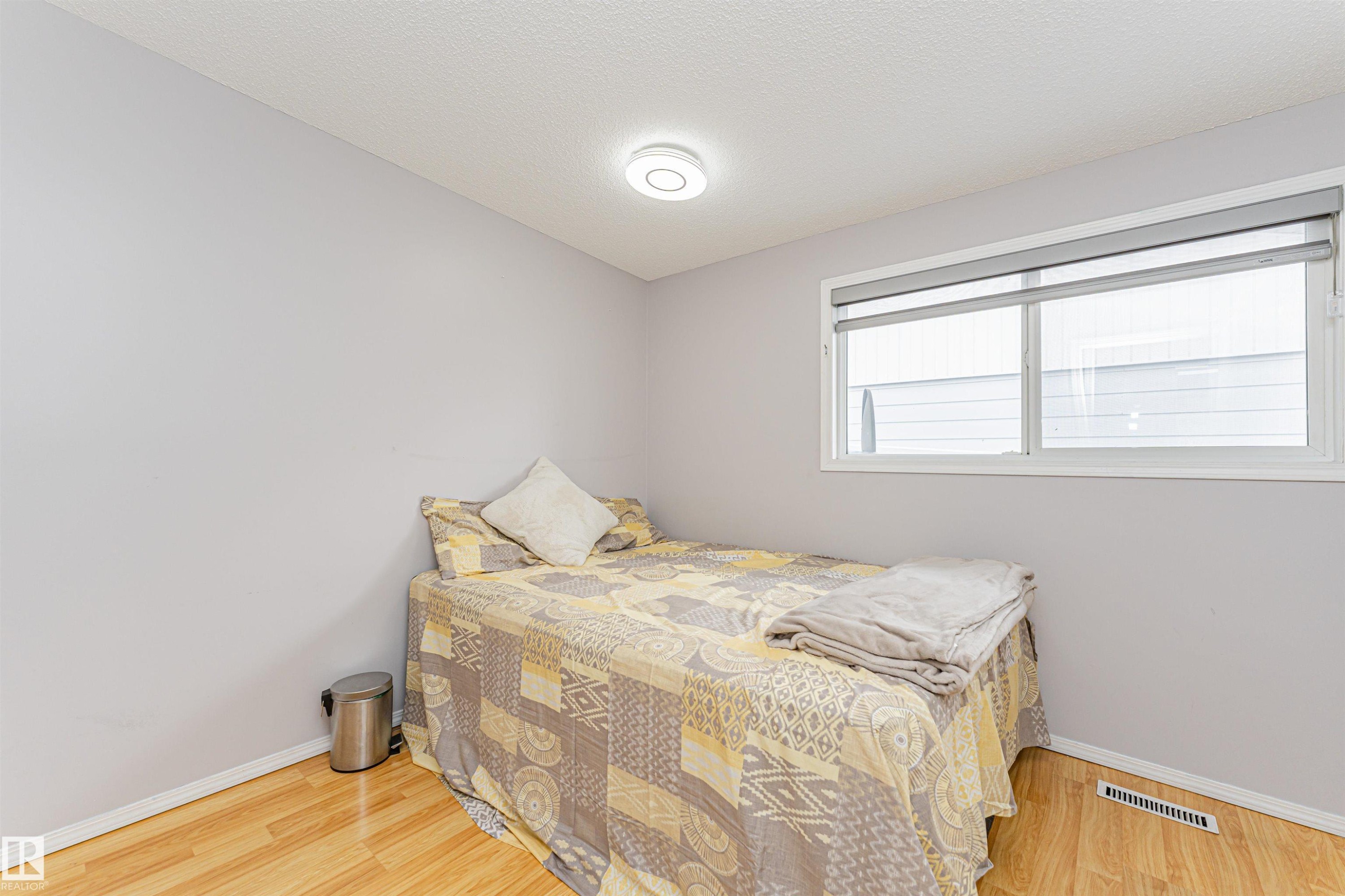 This room features light-colored walls, light wood flooring, and a window with blinds - 10412 39 Avenue, Edmonton, AB - Indoor Photo Showing Bedroom