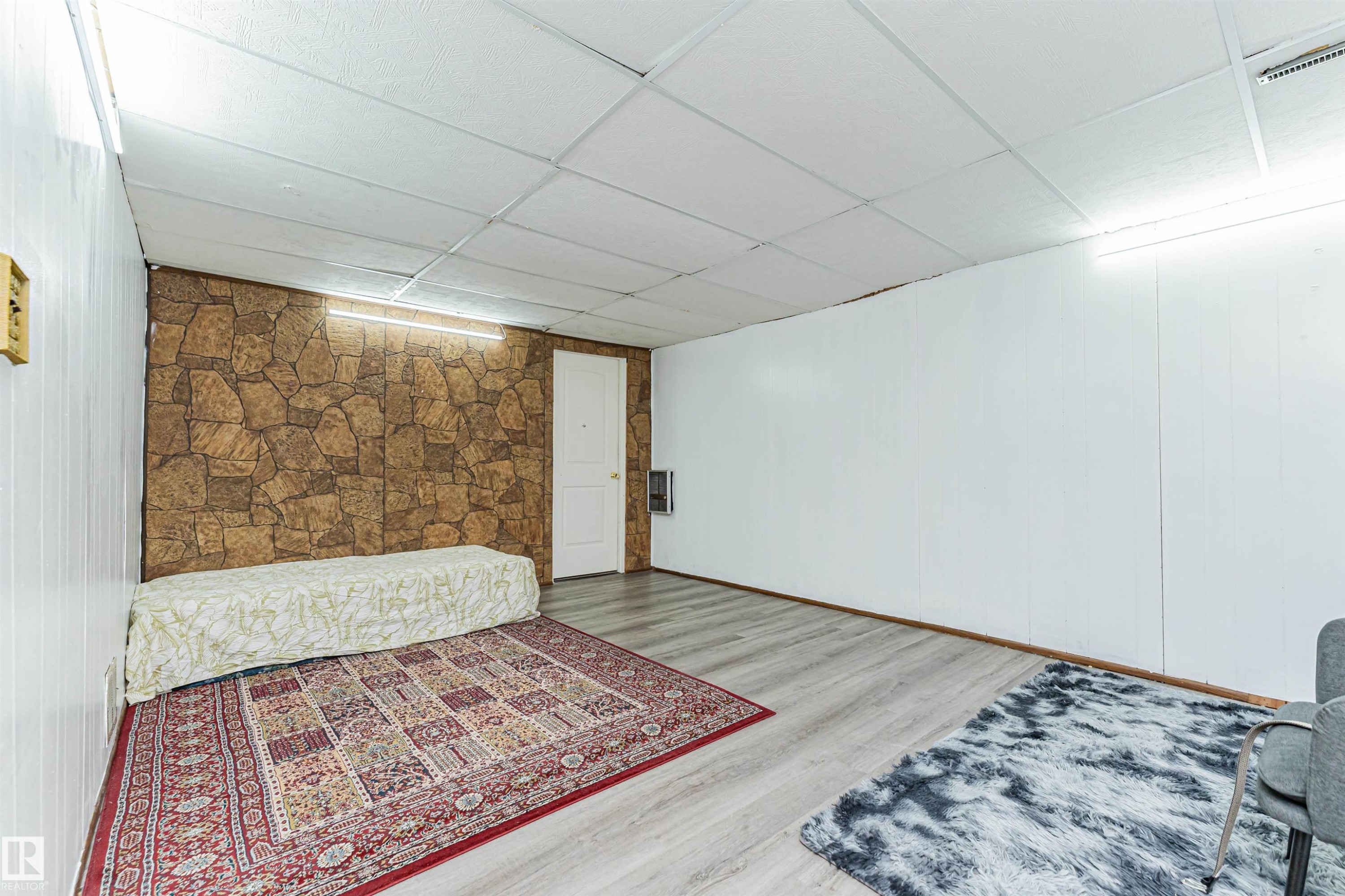 This room features wood plank flooring, white panel walls, and a stone-look accent wall - 10412 39 Avenue, Edmonton, AB - Indoor Photo Showing Other Room